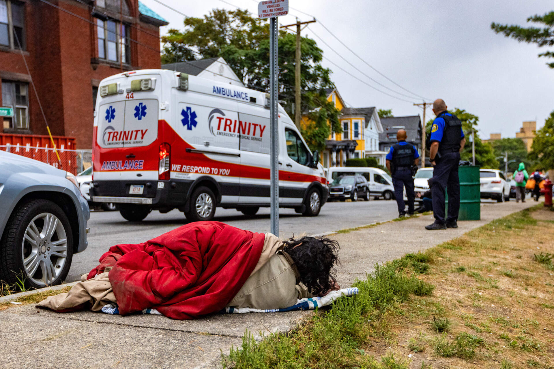 A man lies on the sidewalk on Summer Street next to South Common in Lowell. (Jesse Costa/WBUR)