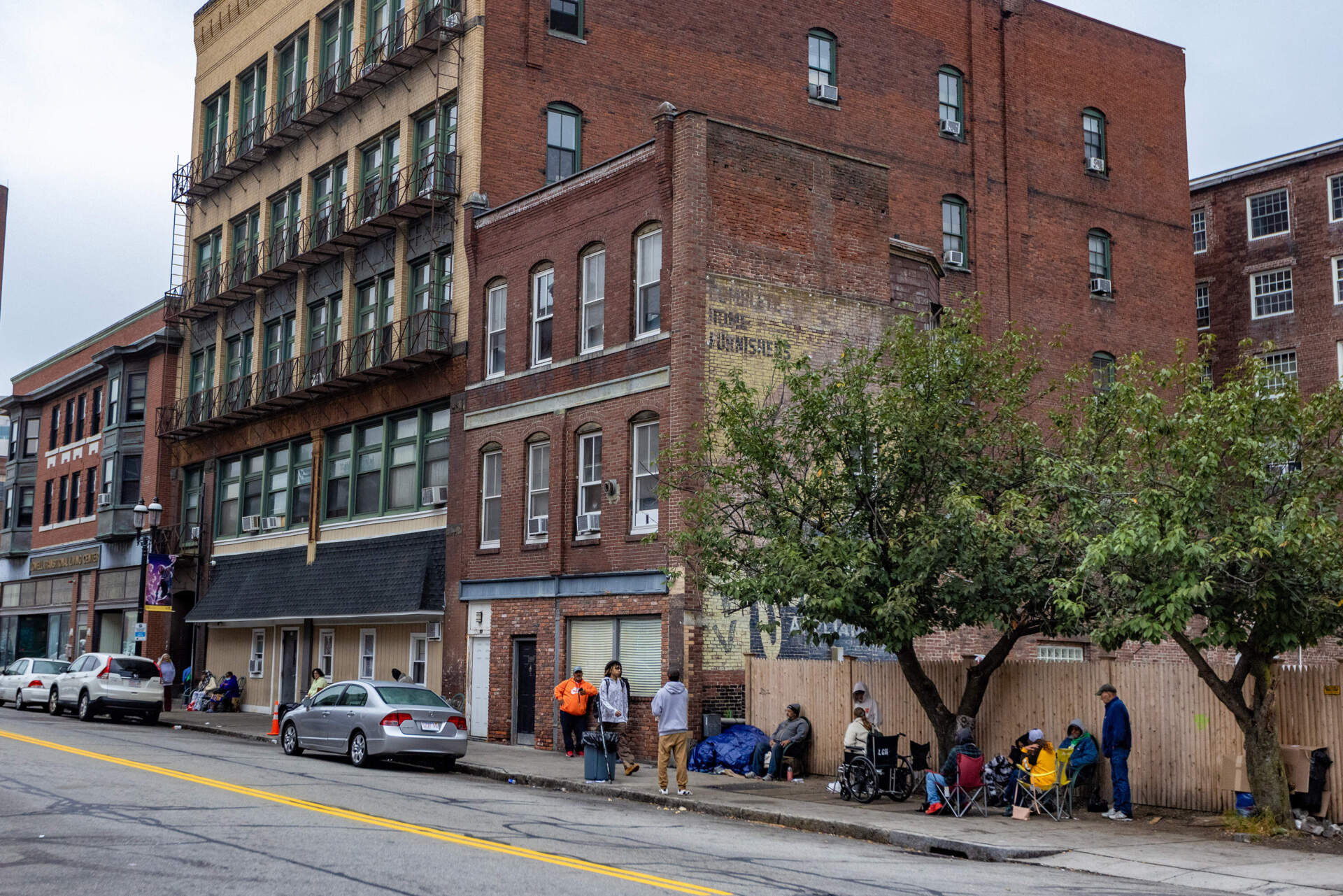People wait outside of the main shelter in Lowell, the Lowell Transitional Living Center. (Jesse Costa/WBUR)