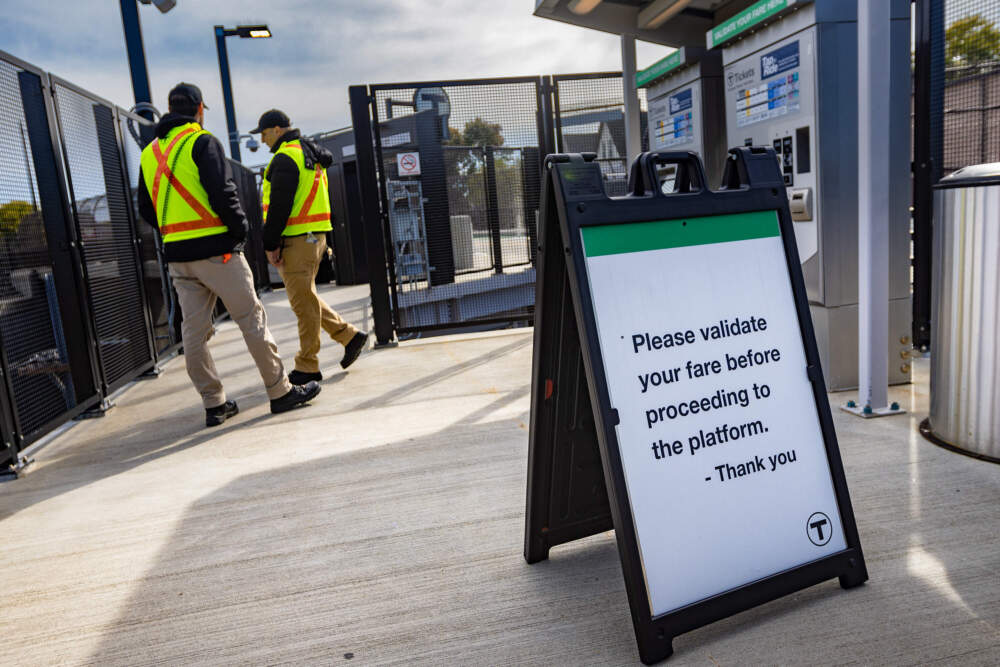 Fare engagement representatives at the MBTA's Magoun Square station along the Green Line Extension wait for riders to answer questions about fares. (Jesse Costa/WBUR)