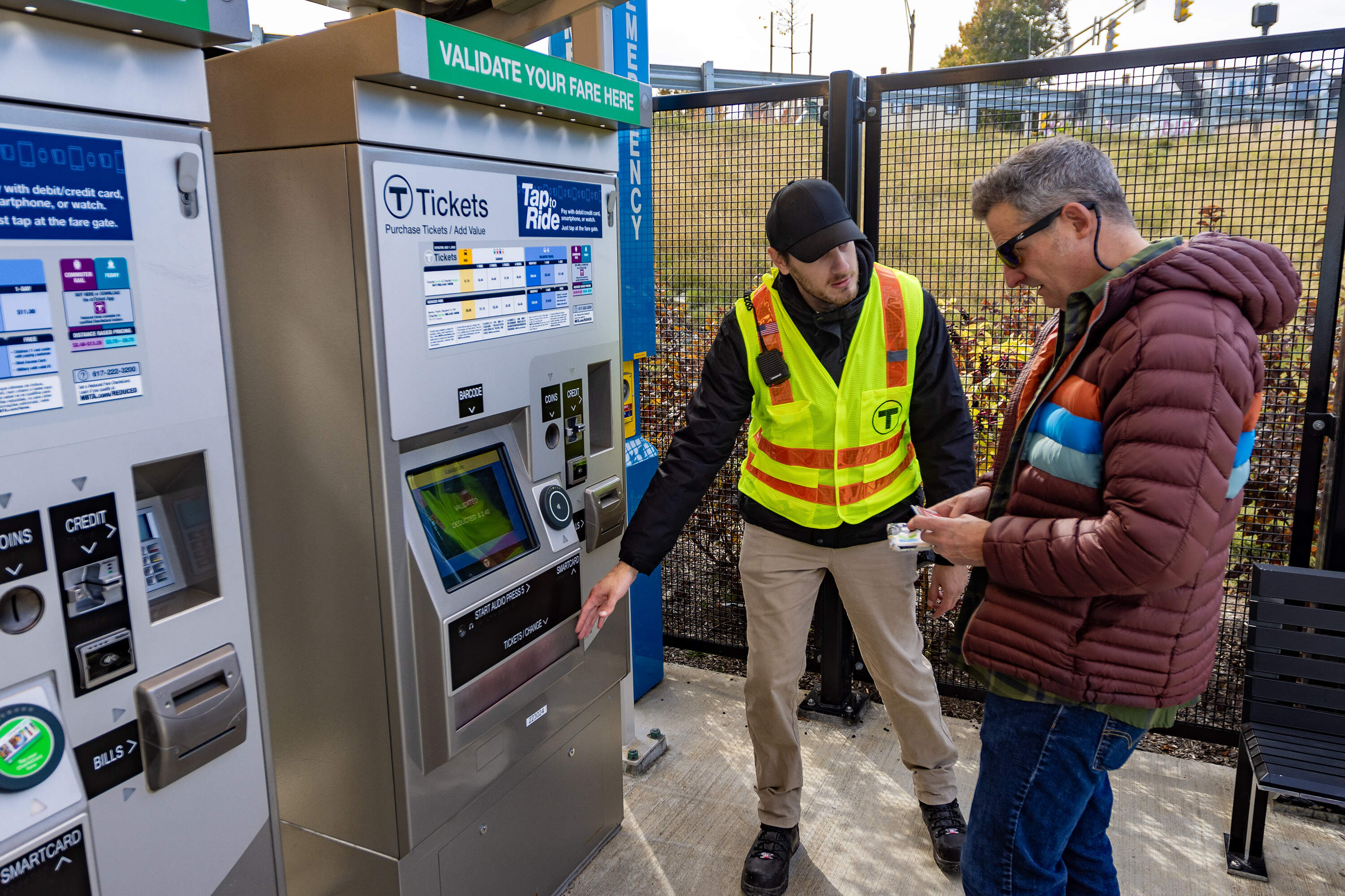 Massimo Ricci assists an MBTA rider in purchasing his fare at the Ball Square station in Medford. (Jesse Costa/WBUR)