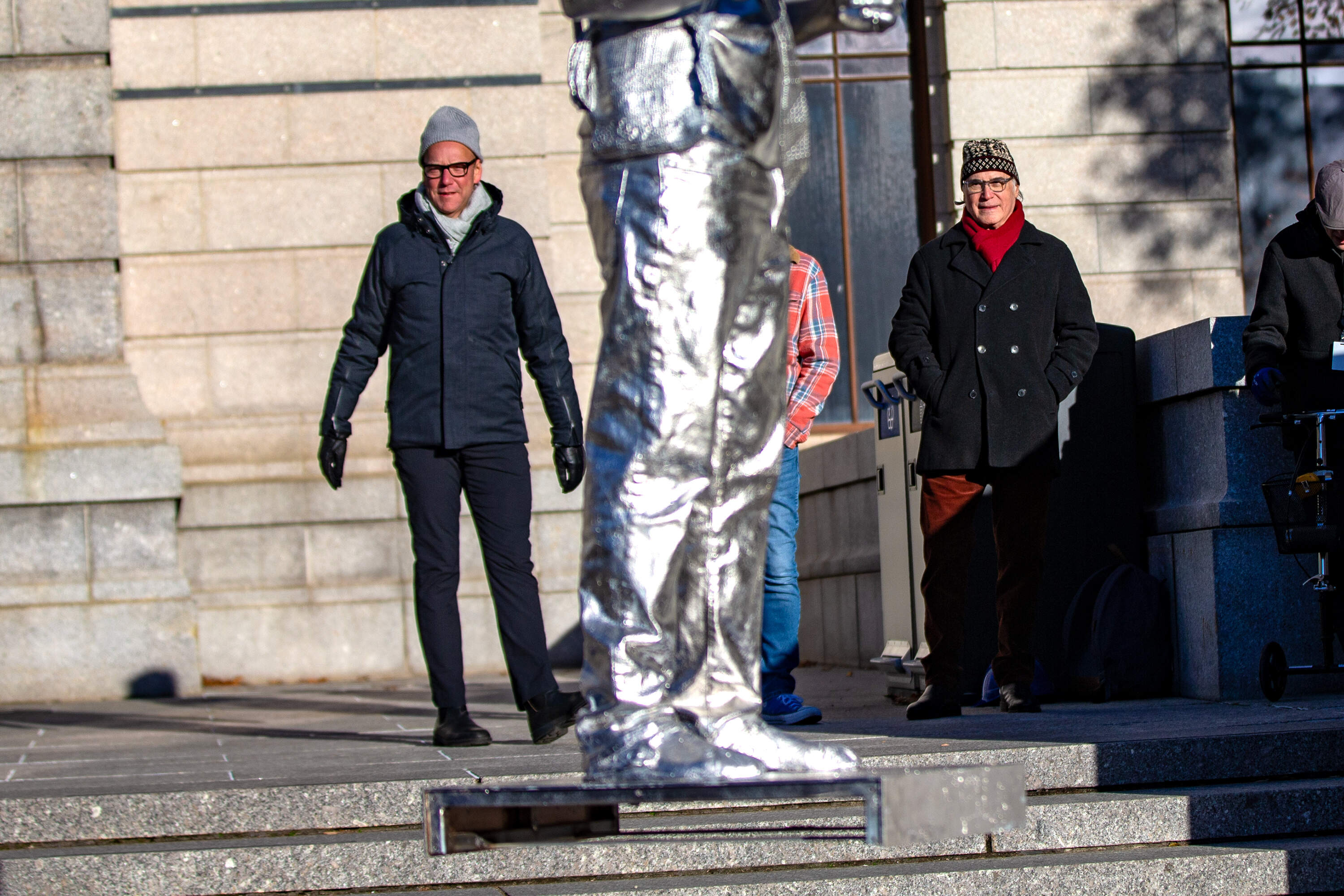 Ian Alteveer, chair of the department of contemporary art, left, and artist Alan Michelson watch as the statue of Nipmuc descendant Andre StrongBearHeart Gaines, Jr is raised to be placed on one of the large plinths outside the Museum of Fine Arts main entrance on Huntington Avenue. (Jesse Costa/WBUR)