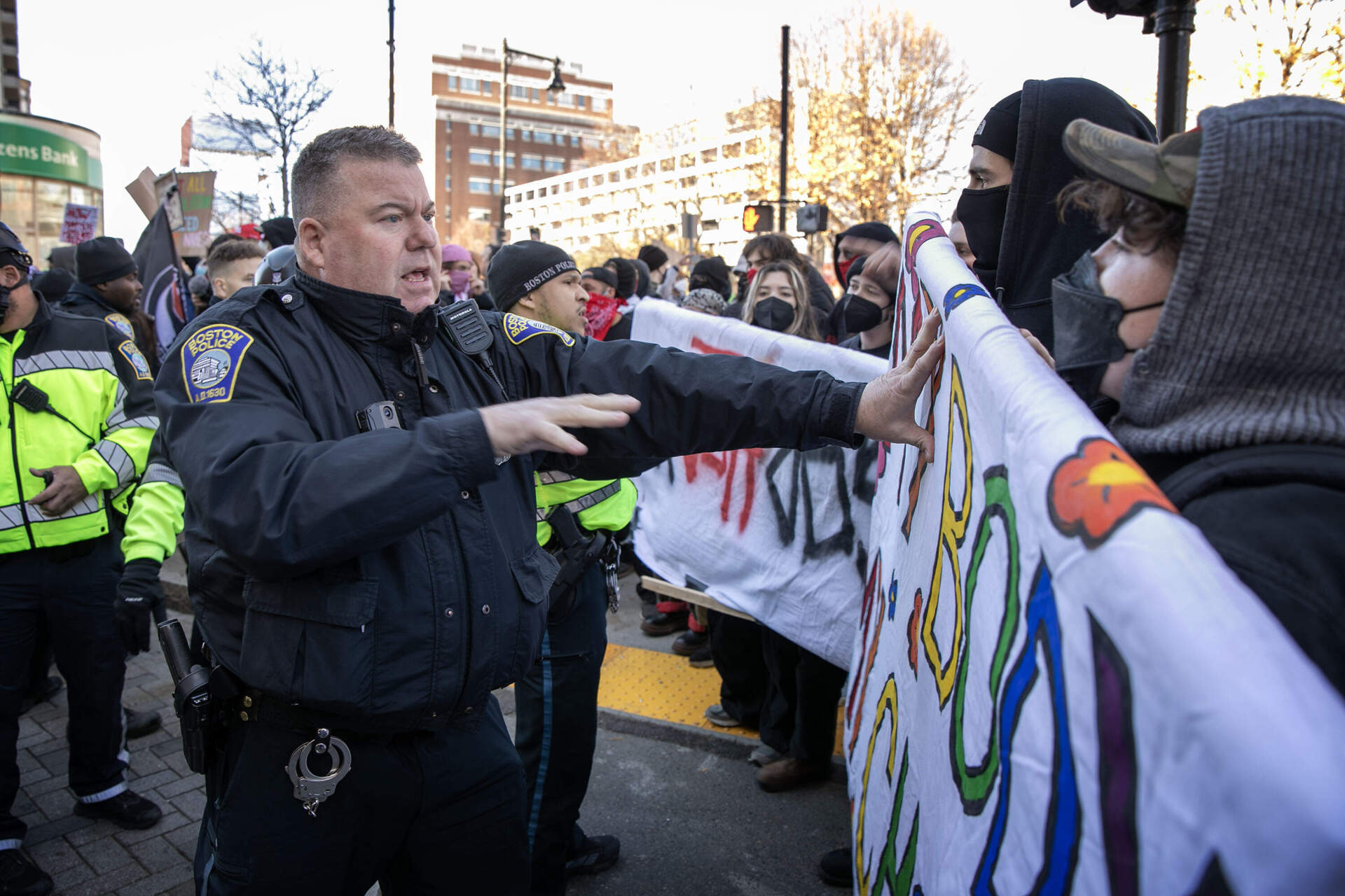 Police officers urge counterprotesters to move back after they block the road at Kenmore Square. (Robin Lubbock/WBUR)
