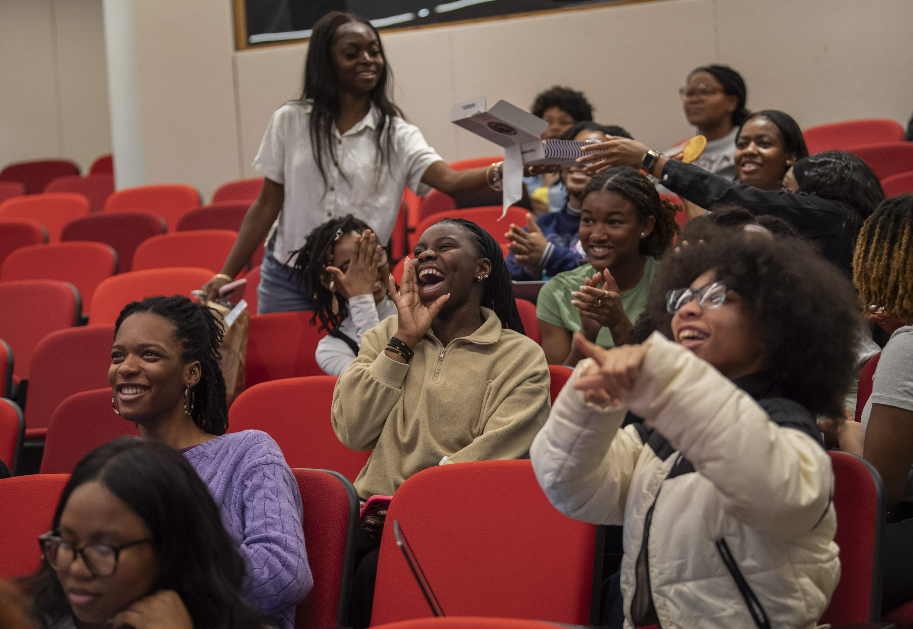 College students cheer as results are projected during an election night watch party at Tufts University for several Boston-area Divine Nine sororities and fraternities including Alpha Kappa Alpha the sorority of Vice President Kamala Harris. (Amanda Sabga for WBUR)