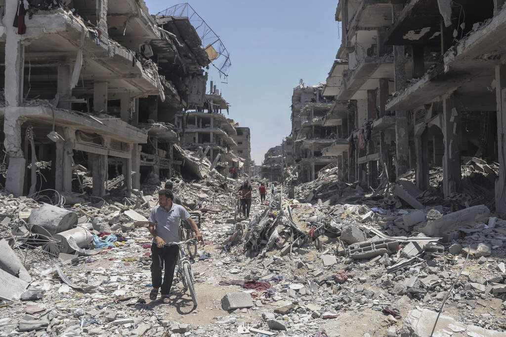 Palestinians walk through the destruction in the wake of an Israeli air and ground offensive in Jebaliya, northern Gaza Strip, Thursday, May 30, 2024. (AP Photo/Enas Rami)