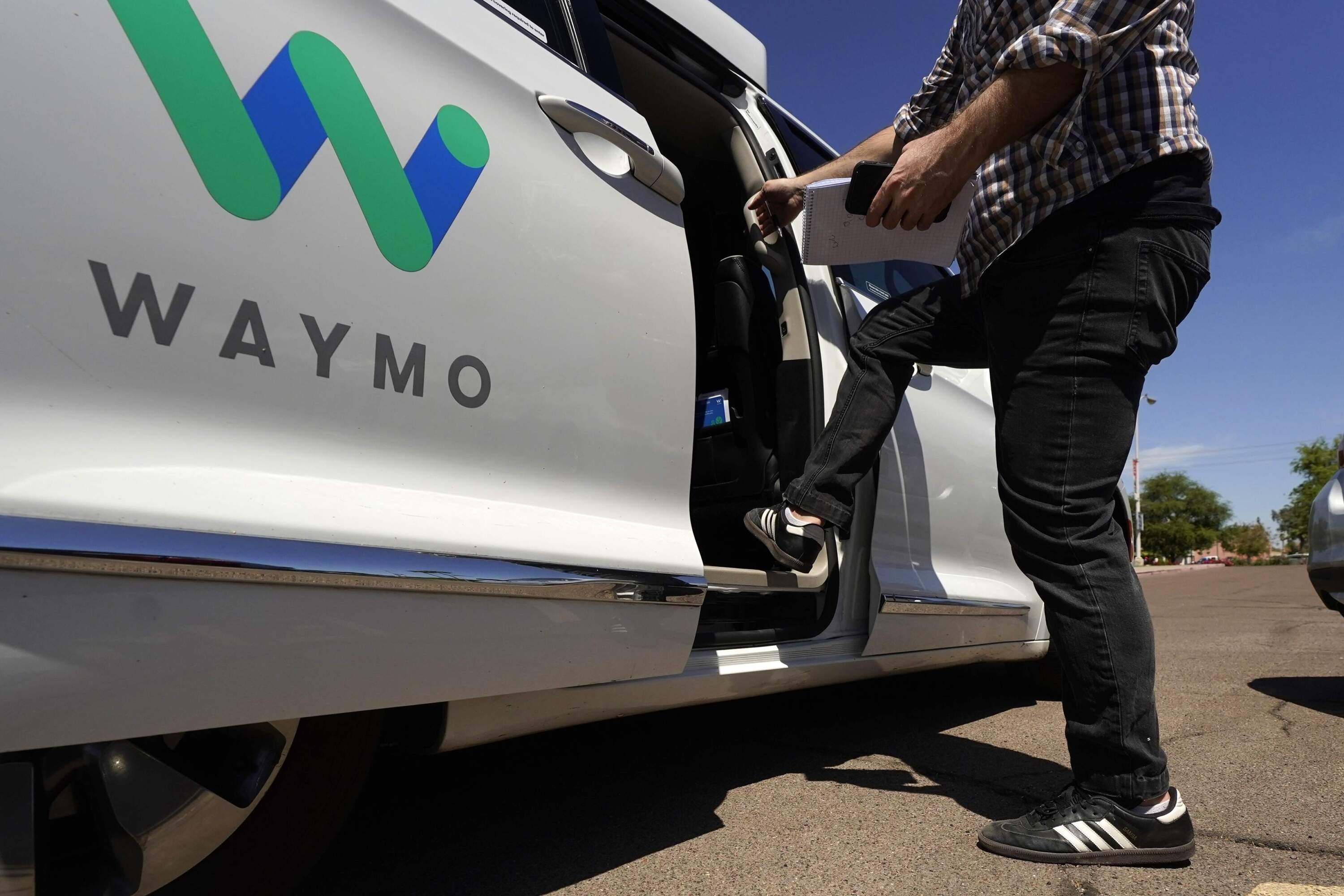 A Waymo minivan arrives to pick up passengers for an autonomous vehicle. (Ross D. Franklin/AP)