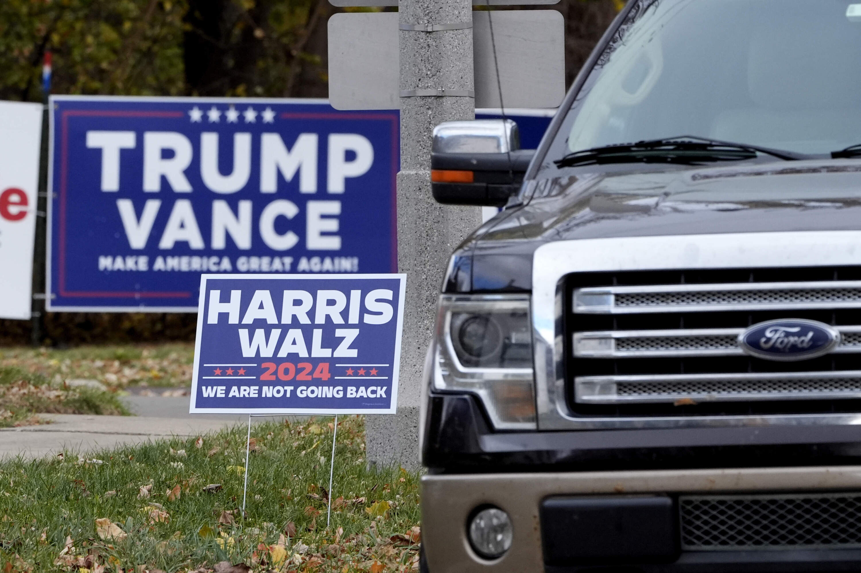 An SUV passes Trump-Vance and Harris-Walz campaign signs. (Charles Rex Arbogast/AP)