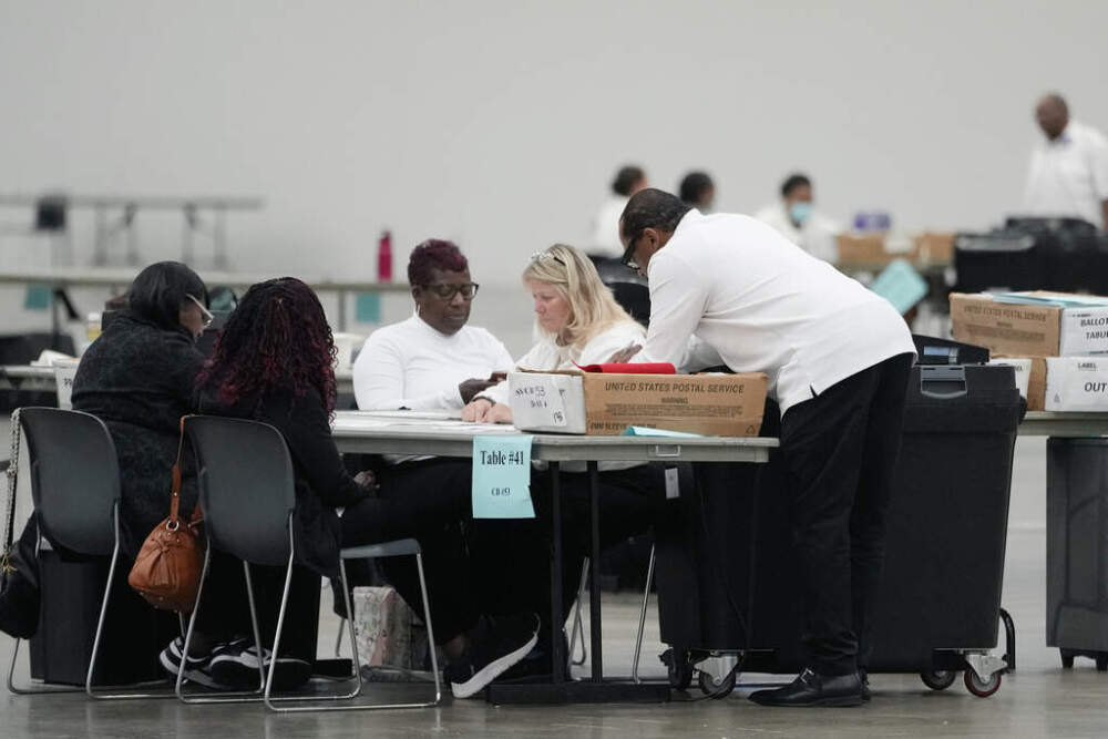 Workers tabulate absentee ballots at the Huntington Place convention center, Thursday, Oct. 31, 2024, in Detroit. Since Monday, about 37,600 absentee ballots already have been counted. (AP Photo/Carlos Osorio)