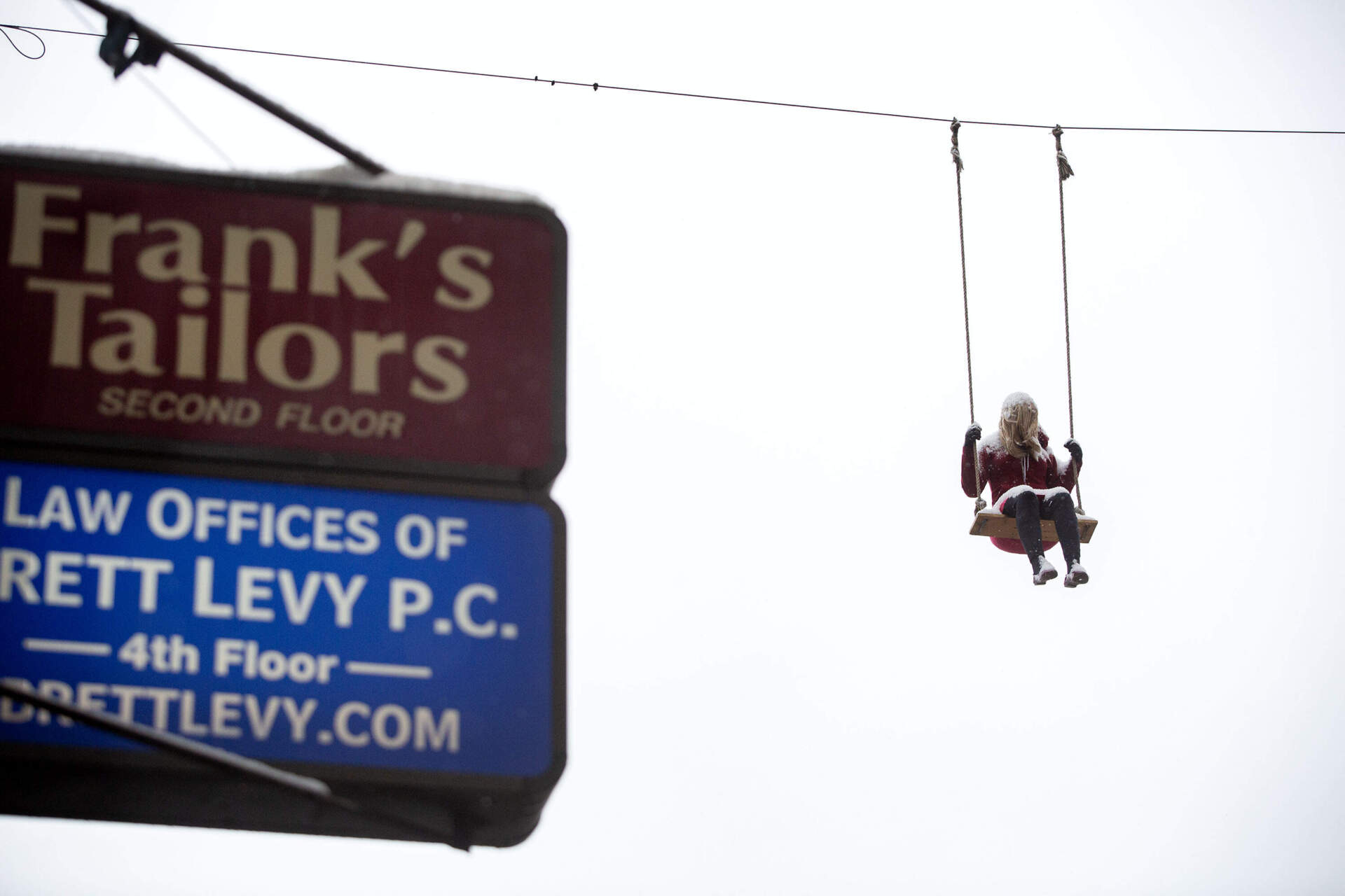 Mark Jenkins' untitled sculpture of a woman on a swing hangs across Winter Street as part of the Downtown Boston Business Improvement District's Winteractive art exhibit. (Robin Lubbock/WBUR)