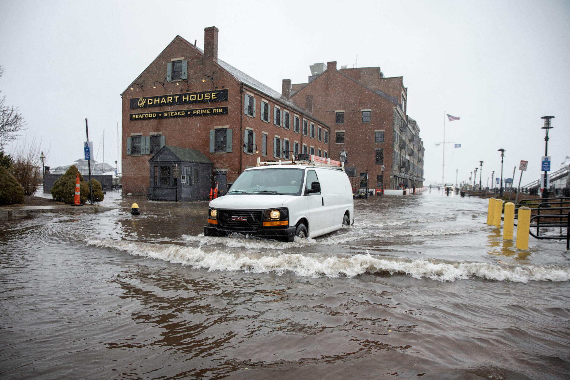 A vehicle pushes its way through seawater flooding across Long Wharf by the Chart House in Boston.