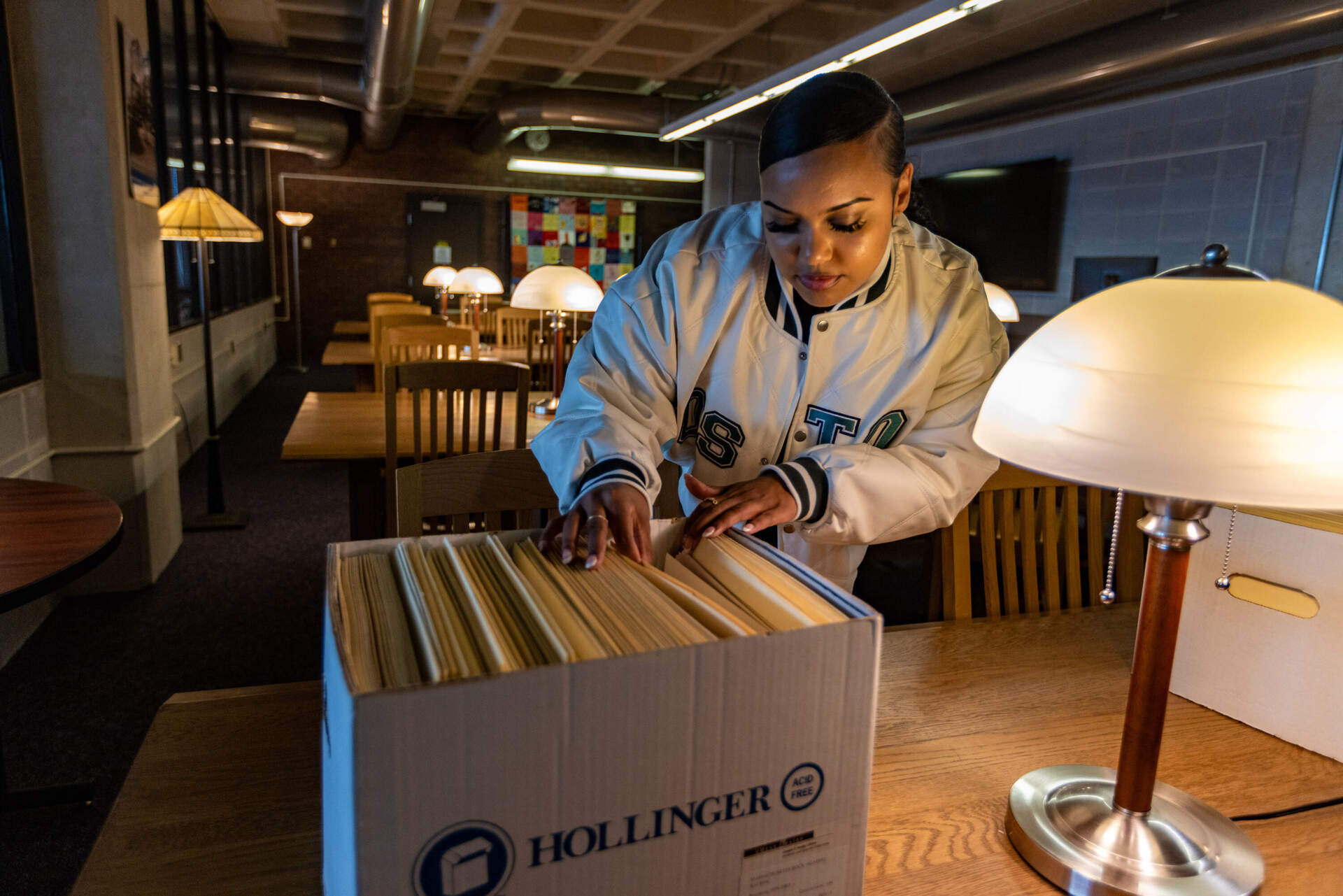 Ebony Gill sifts through the archive of local Boston area music fanzines at the Healey Library at UMASS Boston.