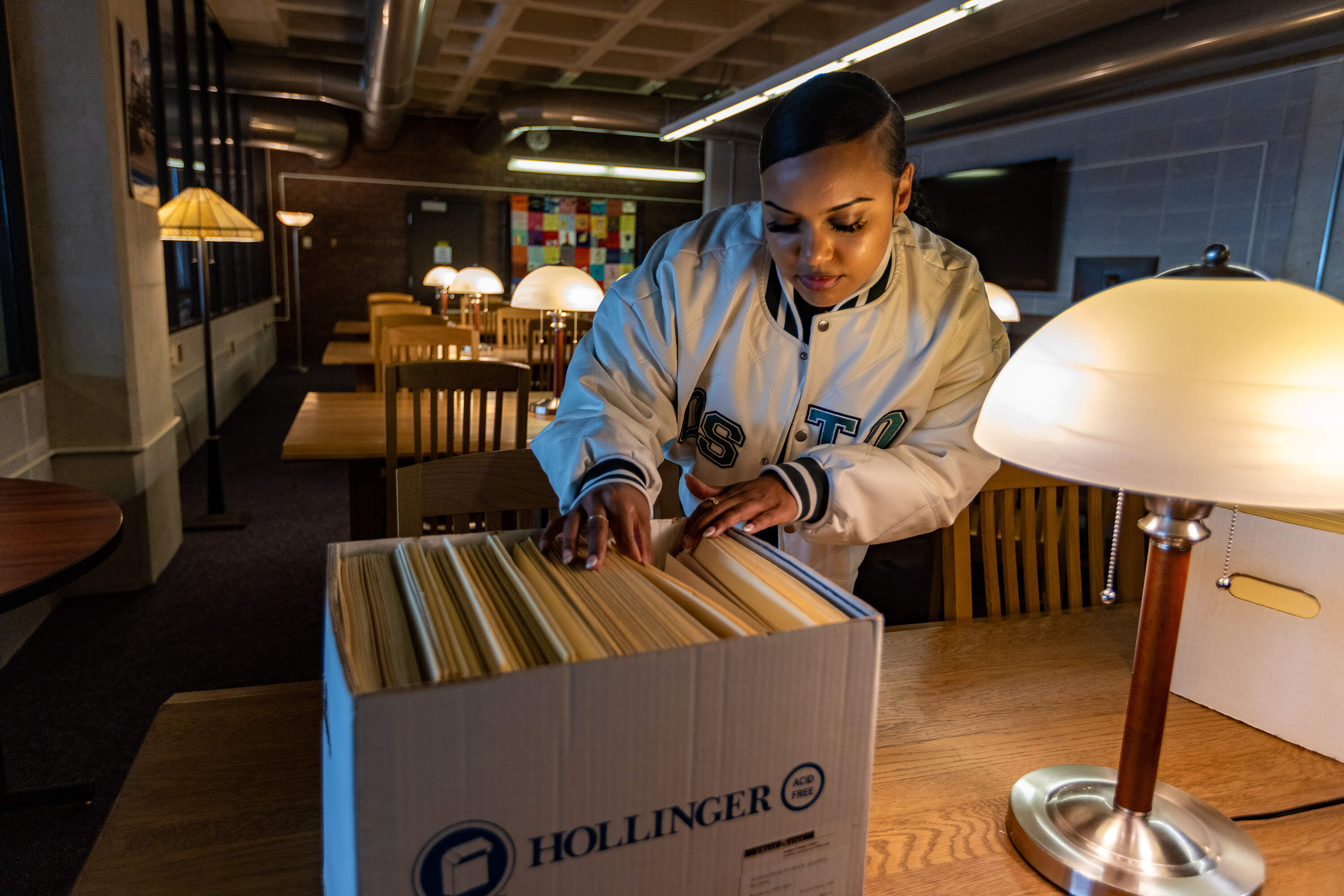 Ebony Gill sifts through the archive of local Boston area music fanzines at the Healey Library at UMASS Boston.