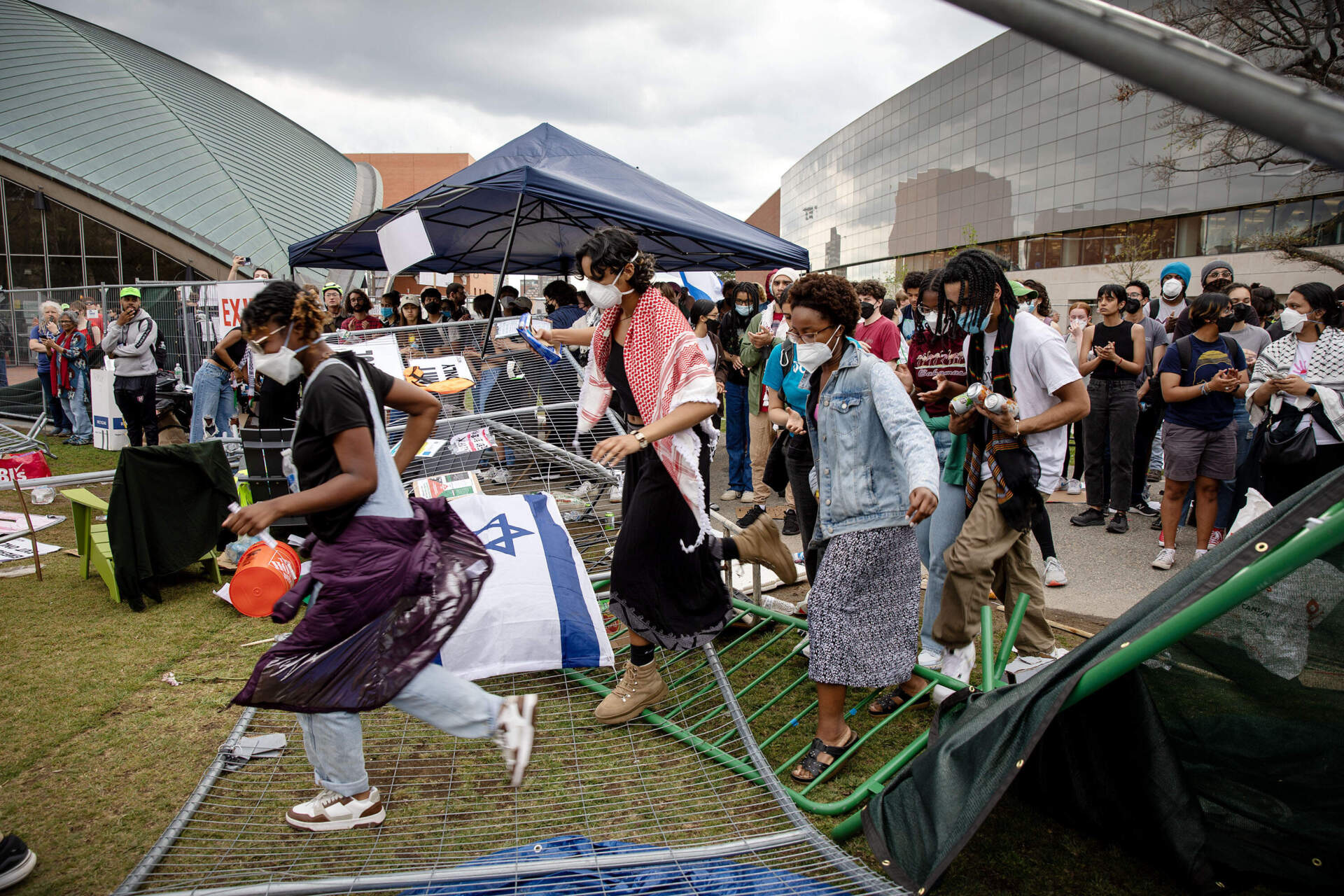 Students cross a flattened metal fence to join other demonstrators re-occupying the student protest encampment at MIT's Kresge Oval.