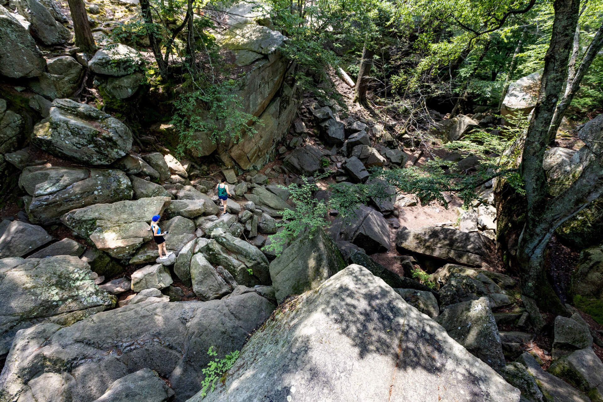 Two people walk through Purgatory Chasm in Sutton on a very hot day.