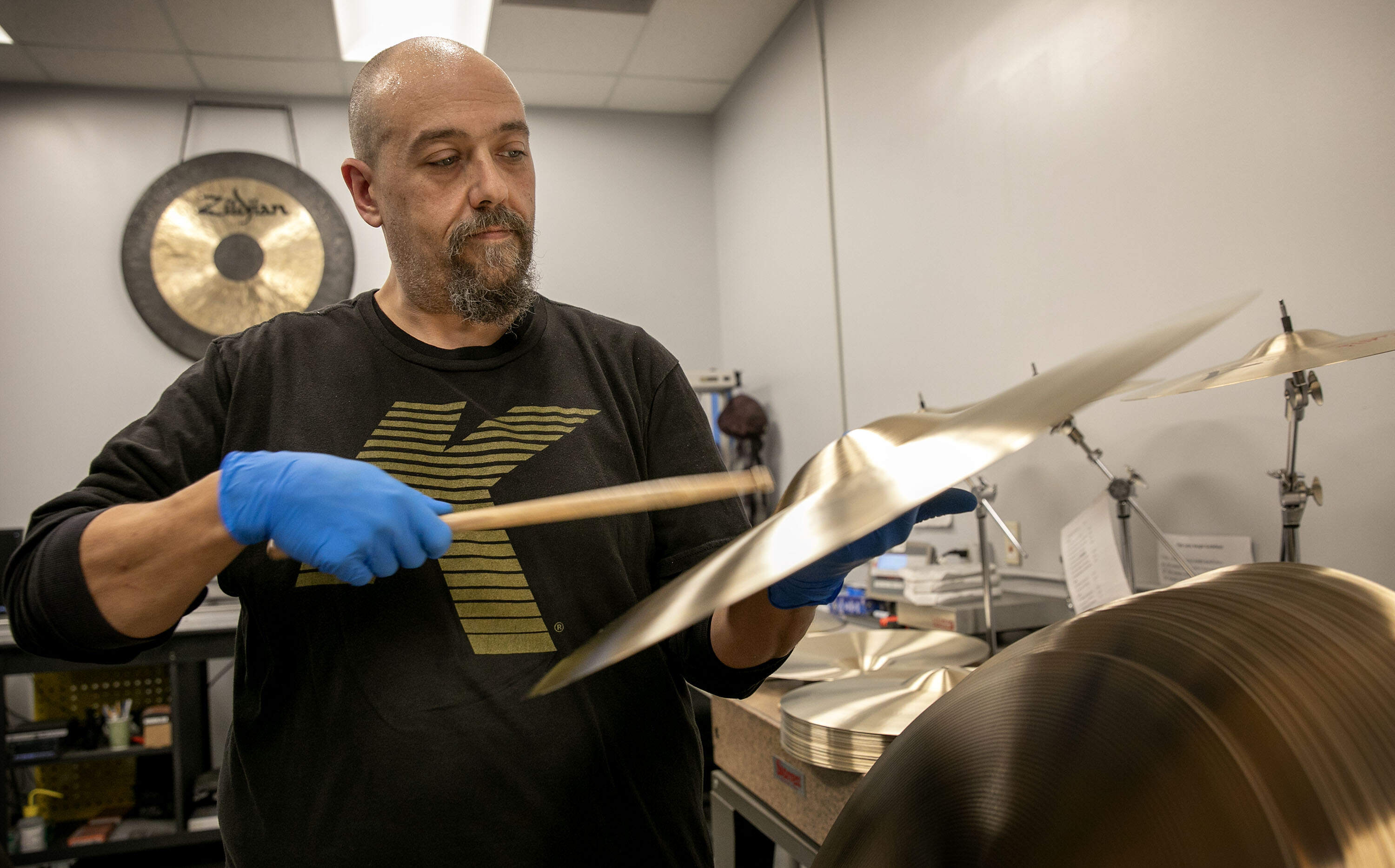 Eric Duncan tests cymbals for quality and sound. (Robin Lubbock/WBUR)