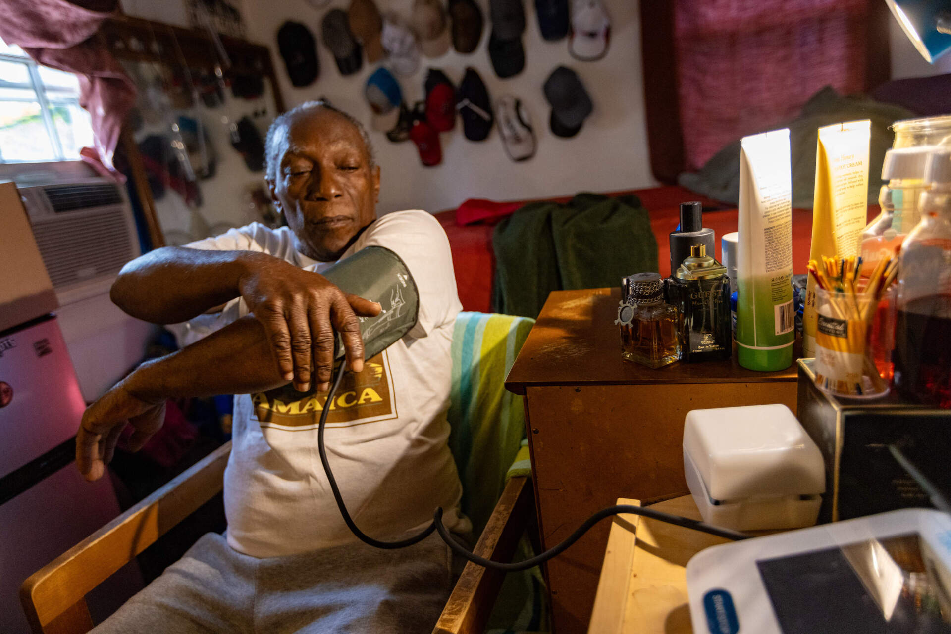 Anthony Brown, at home in Orleans, straps a blood pressure cuff on his arm. (Jesse Costa/WBUR)