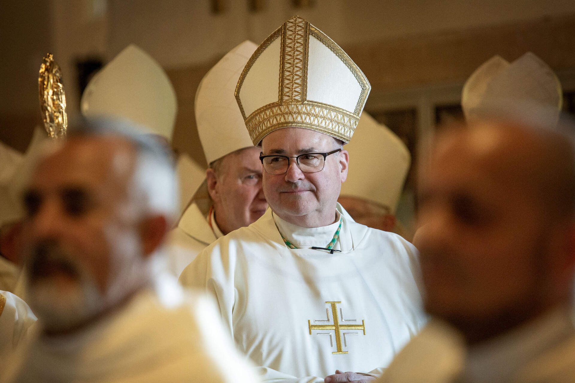 Incoming Archbishop Richard Henning watches as priests walk past him into the Cathedral of the Holy Cross in Boston.