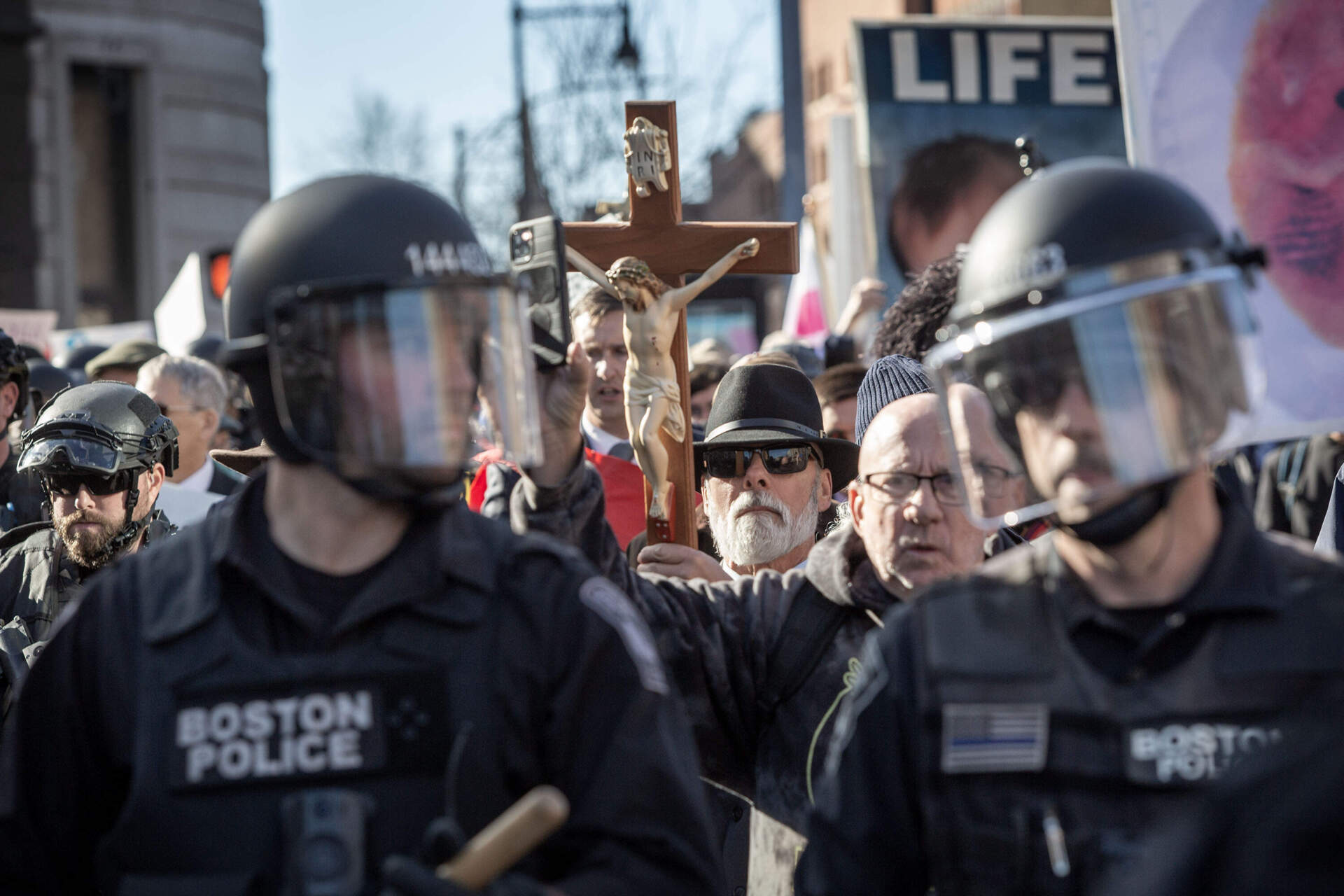 "Men's March" demonstrators stand behind a row of police after counter-protesters block Commonwealth Ave. at Kenmore Square.