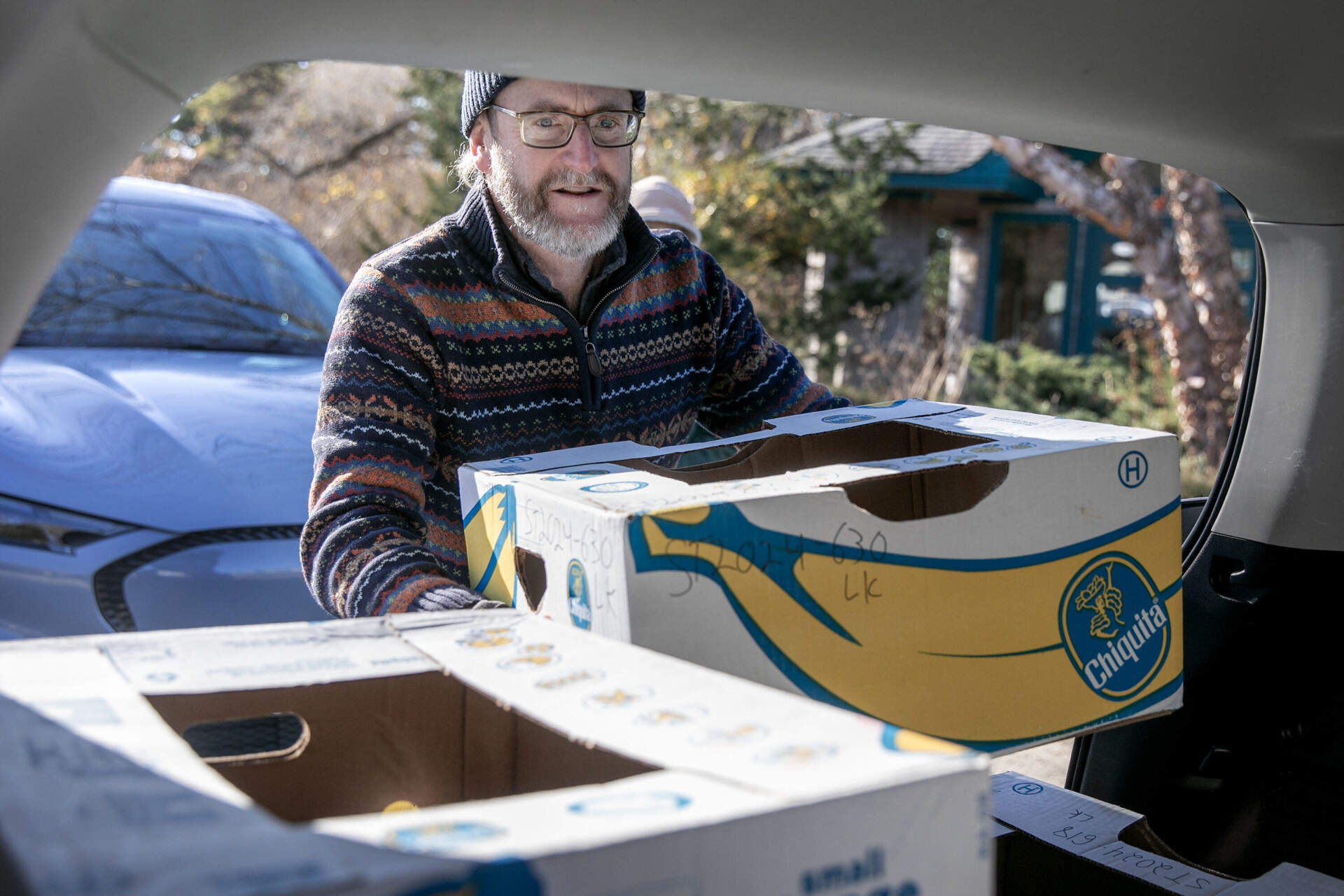 Mark Faherty, science coordinator at Mass Audubon's Wellfleet Bay Wildlife Sanctuary, loads a turtle into a volunteer's car for the trip to the New England Aquarium Animal Care Center in Quincy, Mass. (Robin Lubbock/WBUR)
