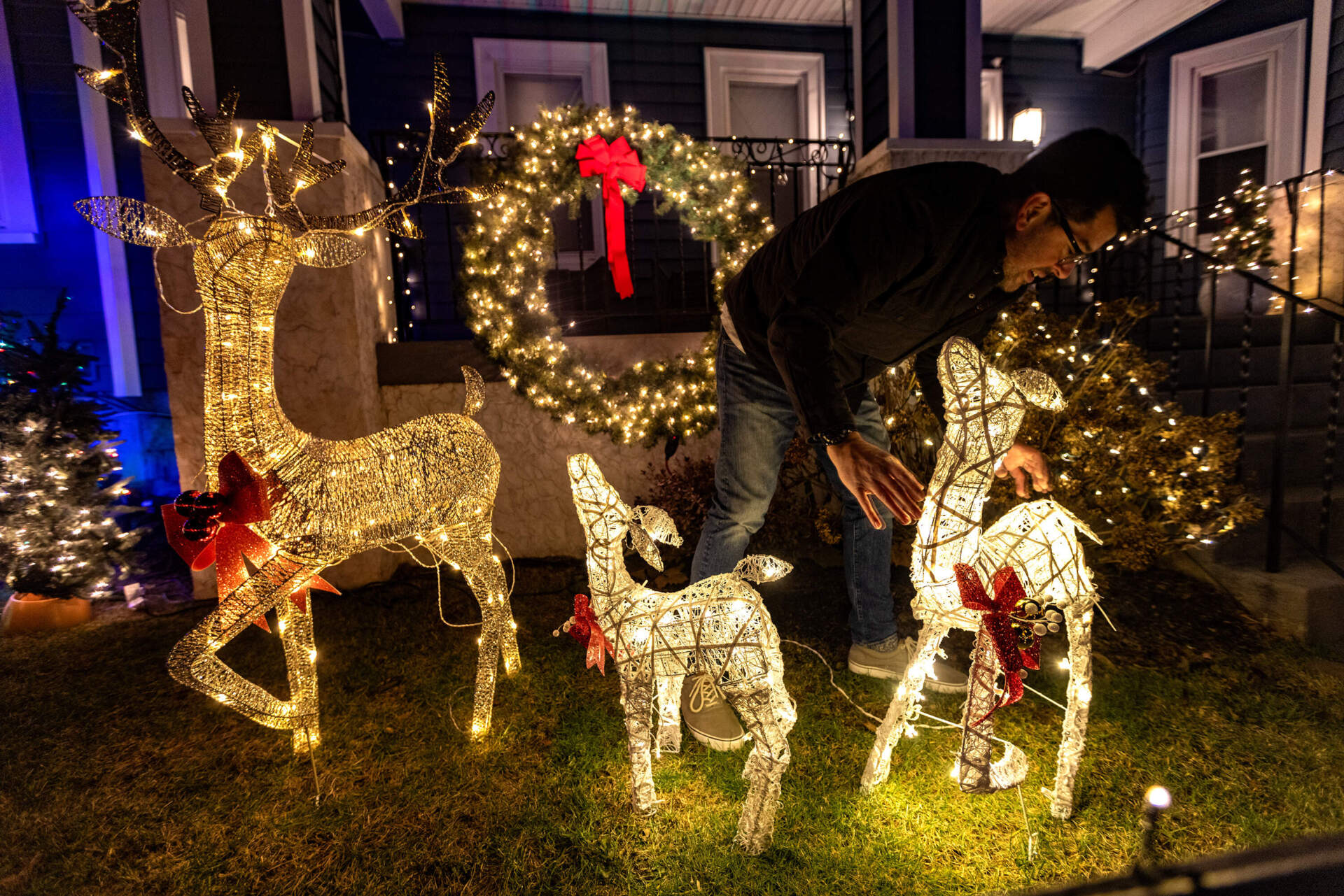 Scott Hosker adjusts the reindeer of his light display in the front yard at 3 Heath Street disheveled by the wind from the storm the day before. (Jesse Costa/WBUR)