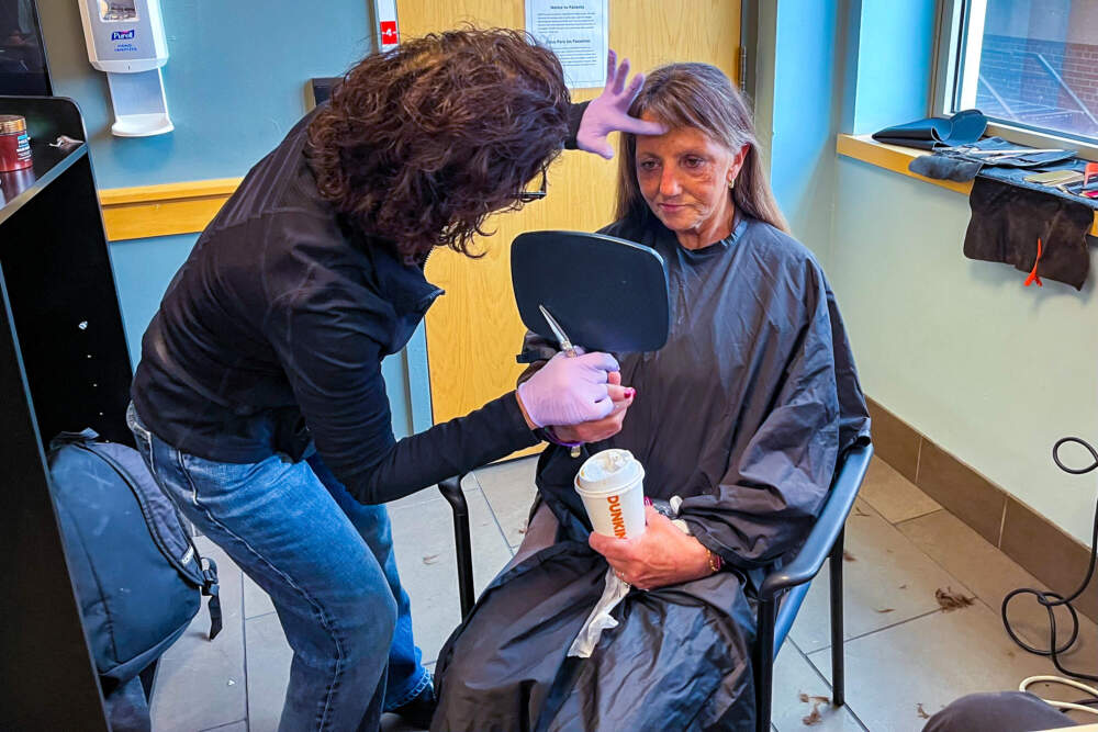 Stylist Joyce Deliyiannis shows Kathleen Cannata her hair after cutting it. Cannata was homeless for several years until she moved into permanent supportive housing last year. (Lynn Jolicoeur/WBUR)