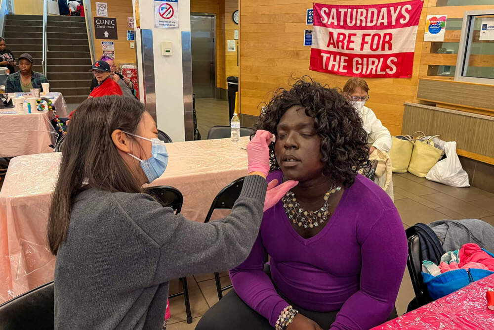 Pinky Valentine, who is unhoused and staying in a shelter, gets her face made up by volunteer Chloe Park. (Lynn Jolicoeur/WBUR)