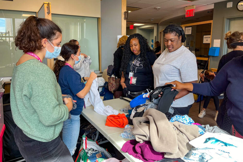 Elaine Joseph, right, picks out clothing as Boston Health Care for the Homeless Program's women's program coordinator Shirley Berard assists and translates for her. (Lynn Jolicoeur/WBUR)