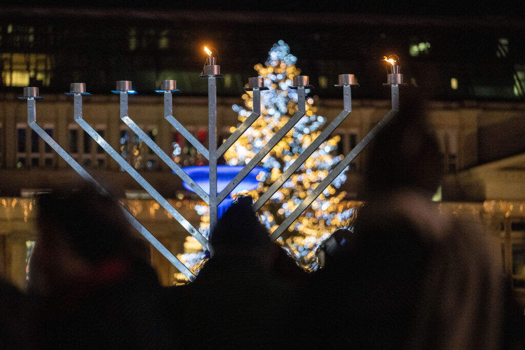 A Hanukkah candelabra stands on Schlossplatz during the ceremonial lighting of the first Hanukkah light, with the illuminated Christmas tree at Stuttgart's Christmas market in the background. (Photo by Marijan Murat/picture alliance via Getty Images)