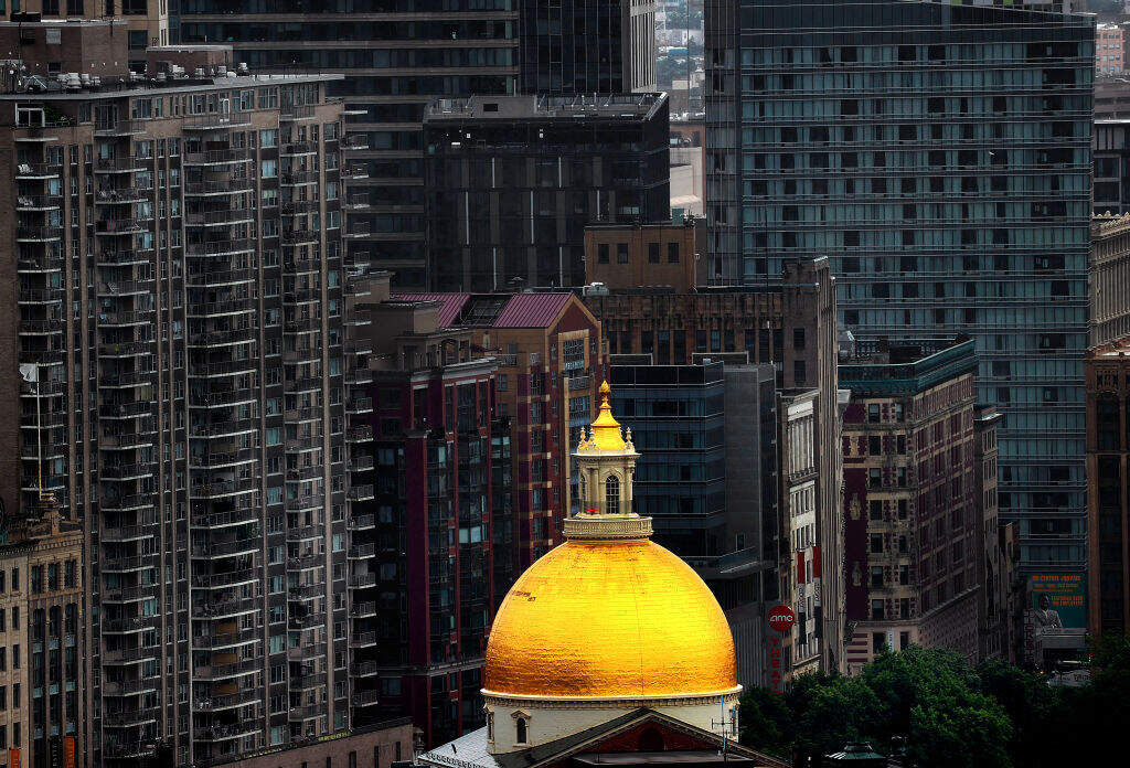 The golden cupola dome of the Massachusetts State House, surrounded by tall buildings. (David L. Ryan/The Boston Globe via Getty Images)