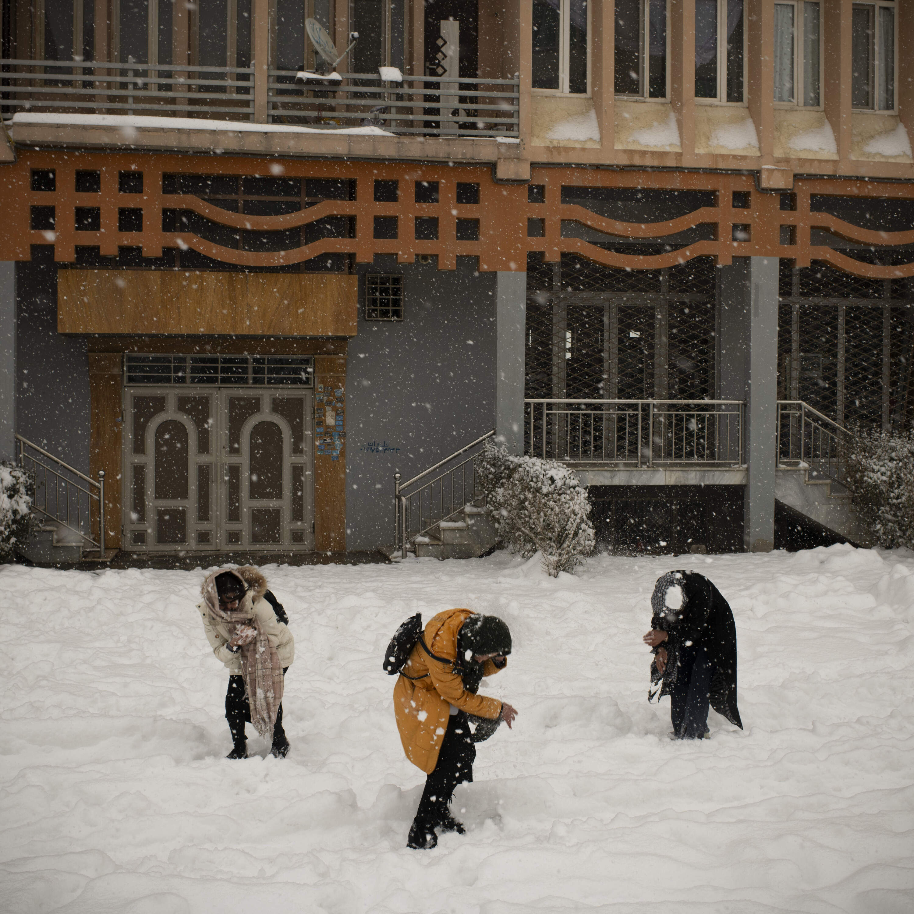 Kabul, Kabul, Afghanistan, February 3, 2024. Girls playing in the snow in western Kabul behind an apartment block, off the main road. Since the takeover, women and girls' rights to move without a male chaperon or to go to parks have been curtailed, and very few opportunities to find joy in their daily lives remain. A snowstorm in a quiet neighbourhood of Kabul western suburb offered such a chance for an hour of playing together. Even then, an eye is always kept on the surroundings, looking for a sign of a Taliban patrol. (KianaHayeri/ Fondation Carmignac)
