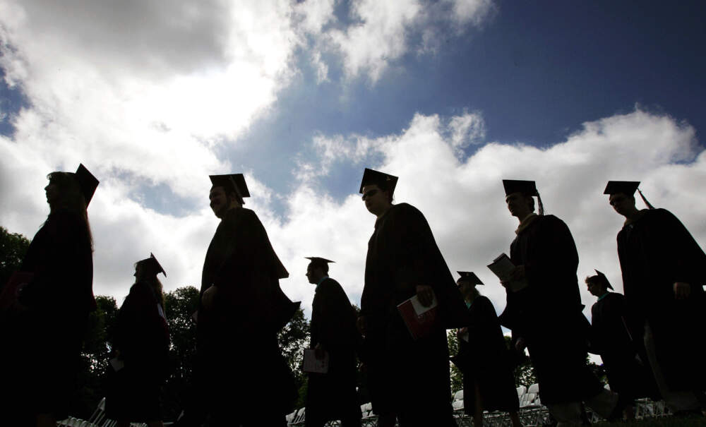 Students in their caps and gowns are silhouetted as they line up for graduation ceremonies. (Mel Evans/AP)