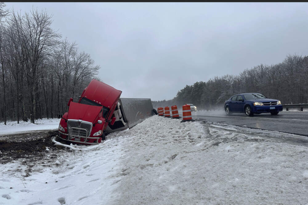 A tractor-trailer hauling a load of oranges sits on the side of the road after sliding off the Maine Turnpike early on Wednesday, Dec. 11, 2024, in New Gloucester, Maine. (David Sharp/AP)