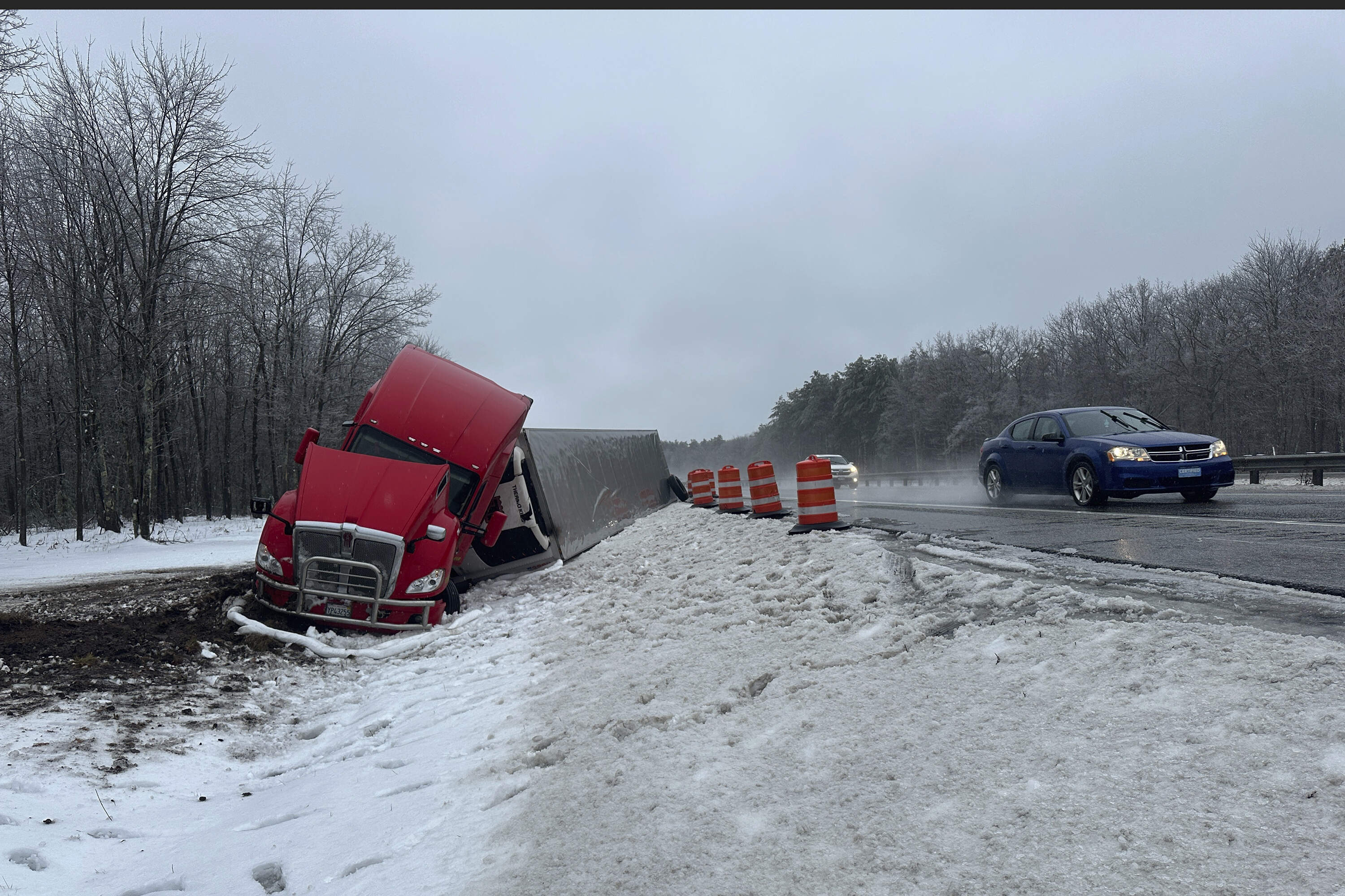 A tractor-trailer hauling a load of oranges sits on the side of the road after sliding off the Maine Turnpike early on Wednesday, Dec. 11, 2024, in New Gloucester, Maine. (David Sharp/AP)