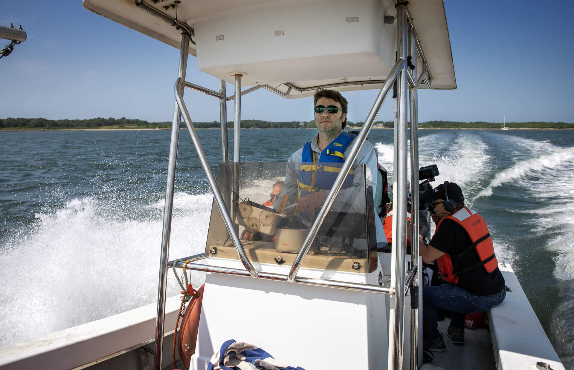 Woods Hole Oceanographic Institution scientist Matthew Long pilots the dive boat out to eelgrass beds. (Robin Lubbock/WBUR)