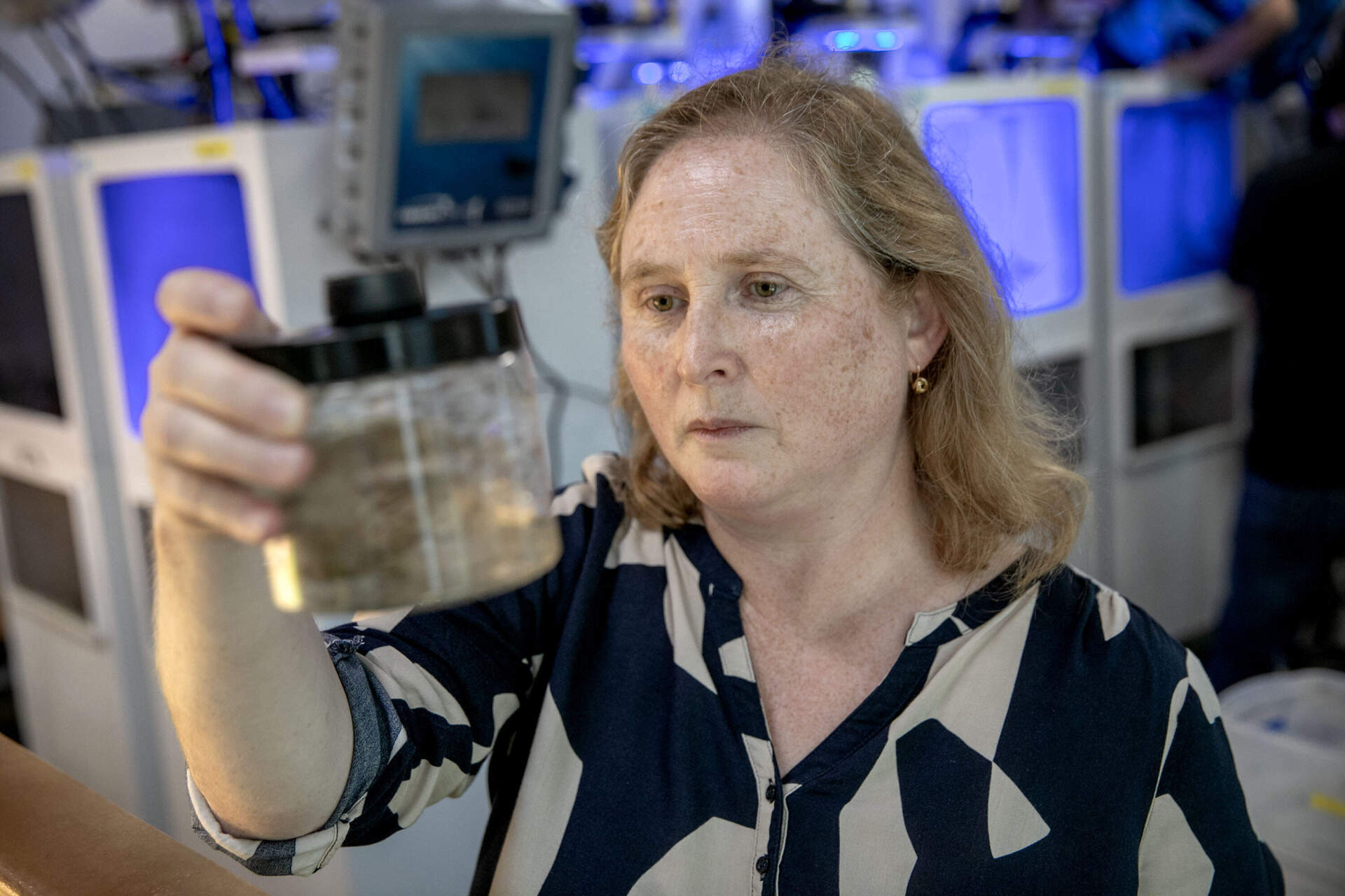 Mirta Teichberg, a scientist at the Marine Biological Laboratory, examines a jar of water gathered from the lab's eelgrass tanks. (Robin Lubbock/WBUR)