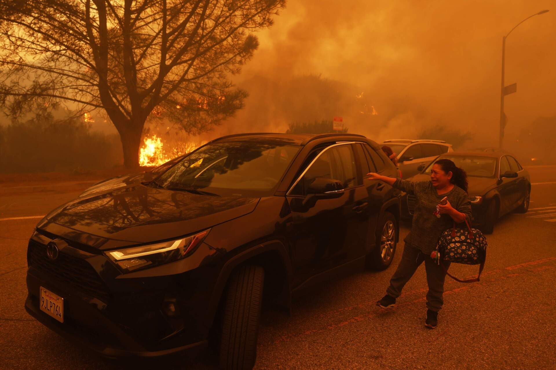A woman cries as the Palisades Fire advances in the Pacific Palisades neighborhood of Los Angeles on Tuesday. (Etienne Laurent/AP)
