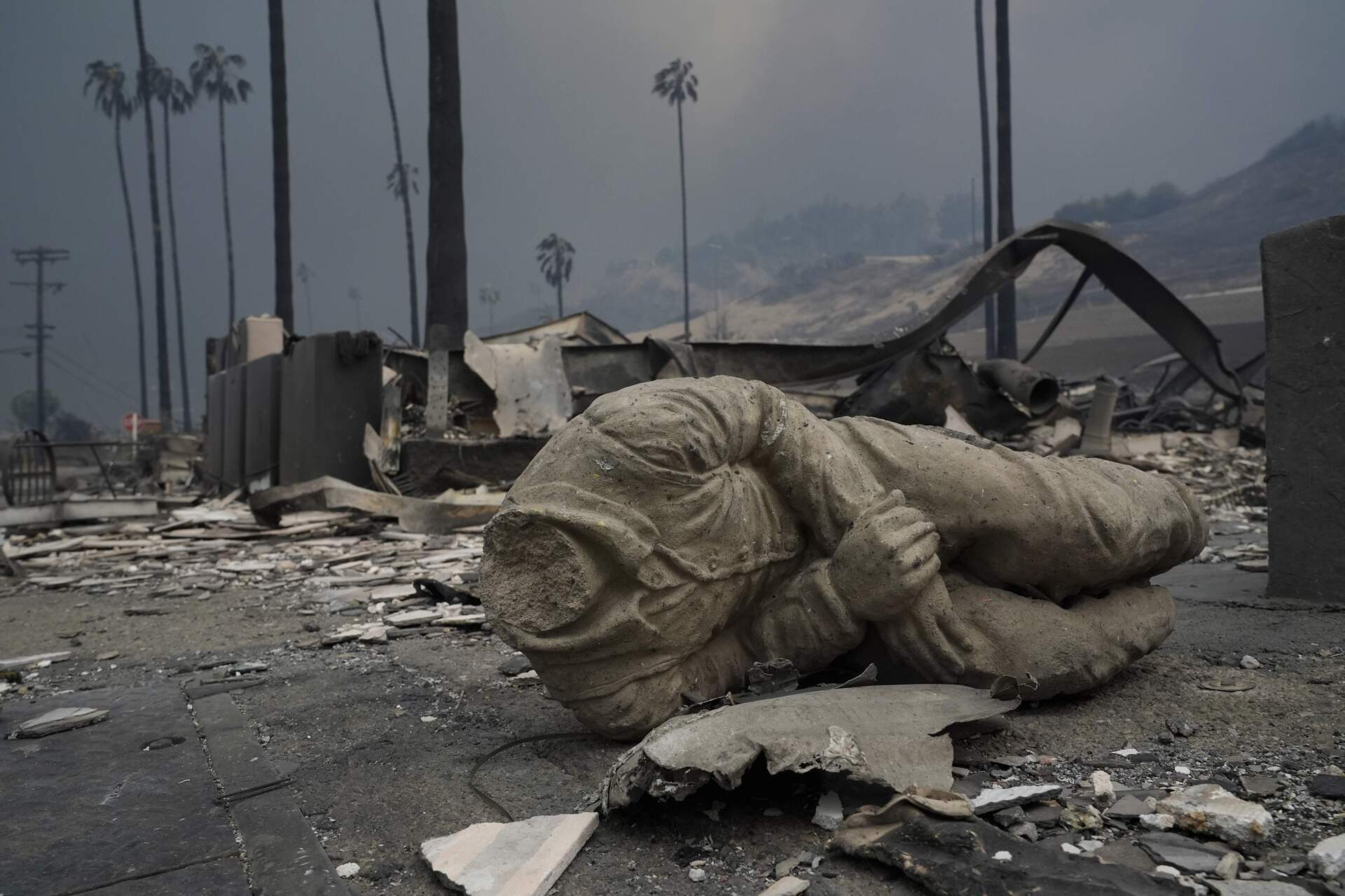 A statue and other structures are burned as the Palisades Fire ravages a neighborhood amid high winds on Wednesday. (Damian Dovarganes/AP)