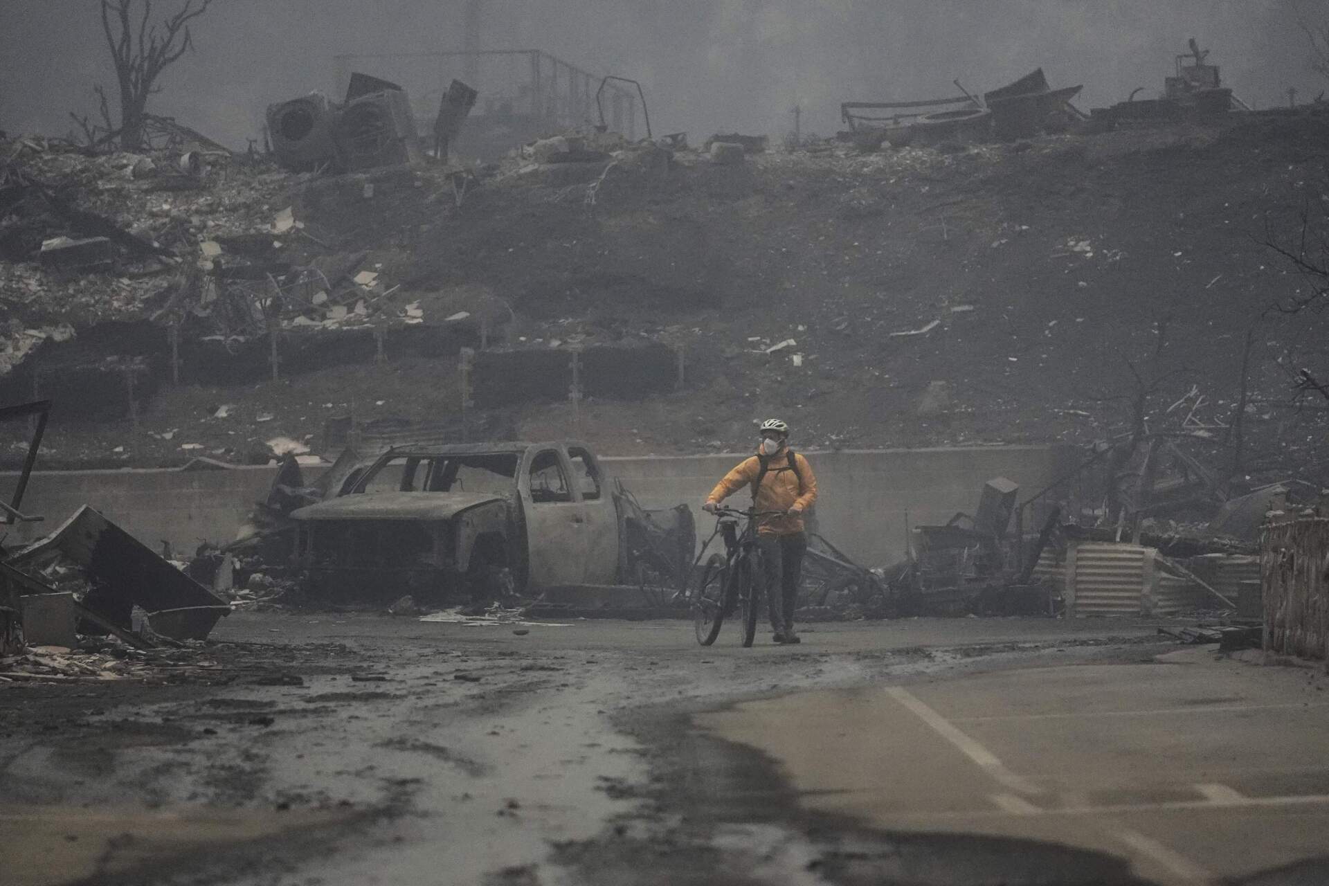 A man walks his bike among the ruins left behind by the Palisades Fire in the Pacific Palisades neighborhood on Wednesday. (Damian Dovarganes/AP)