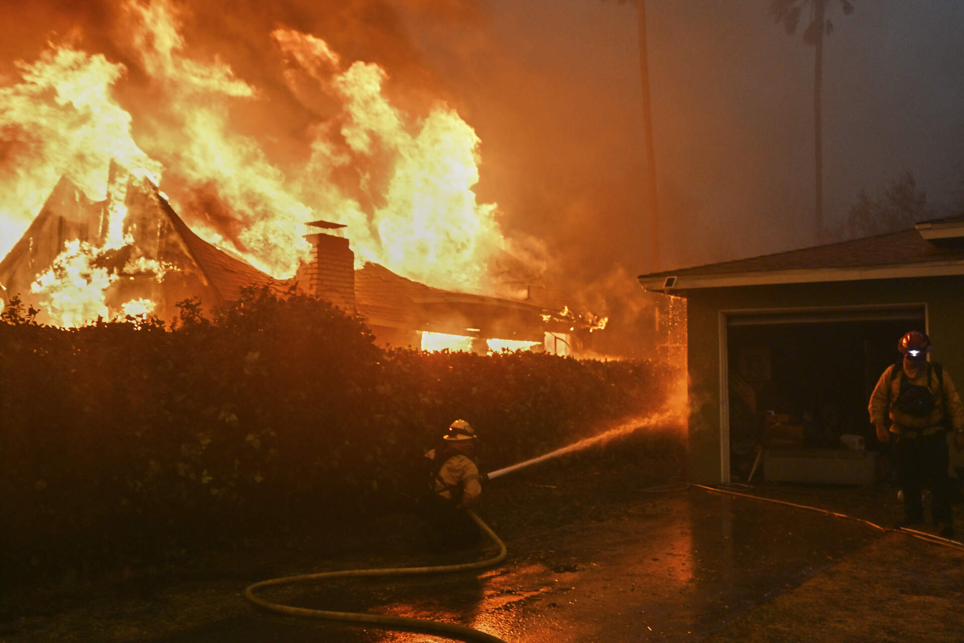 Fire crews battle the Eaton Fire next to a fully engulfed residence on Wednesday in Altadena, Calif. (Nic Coury/AP)