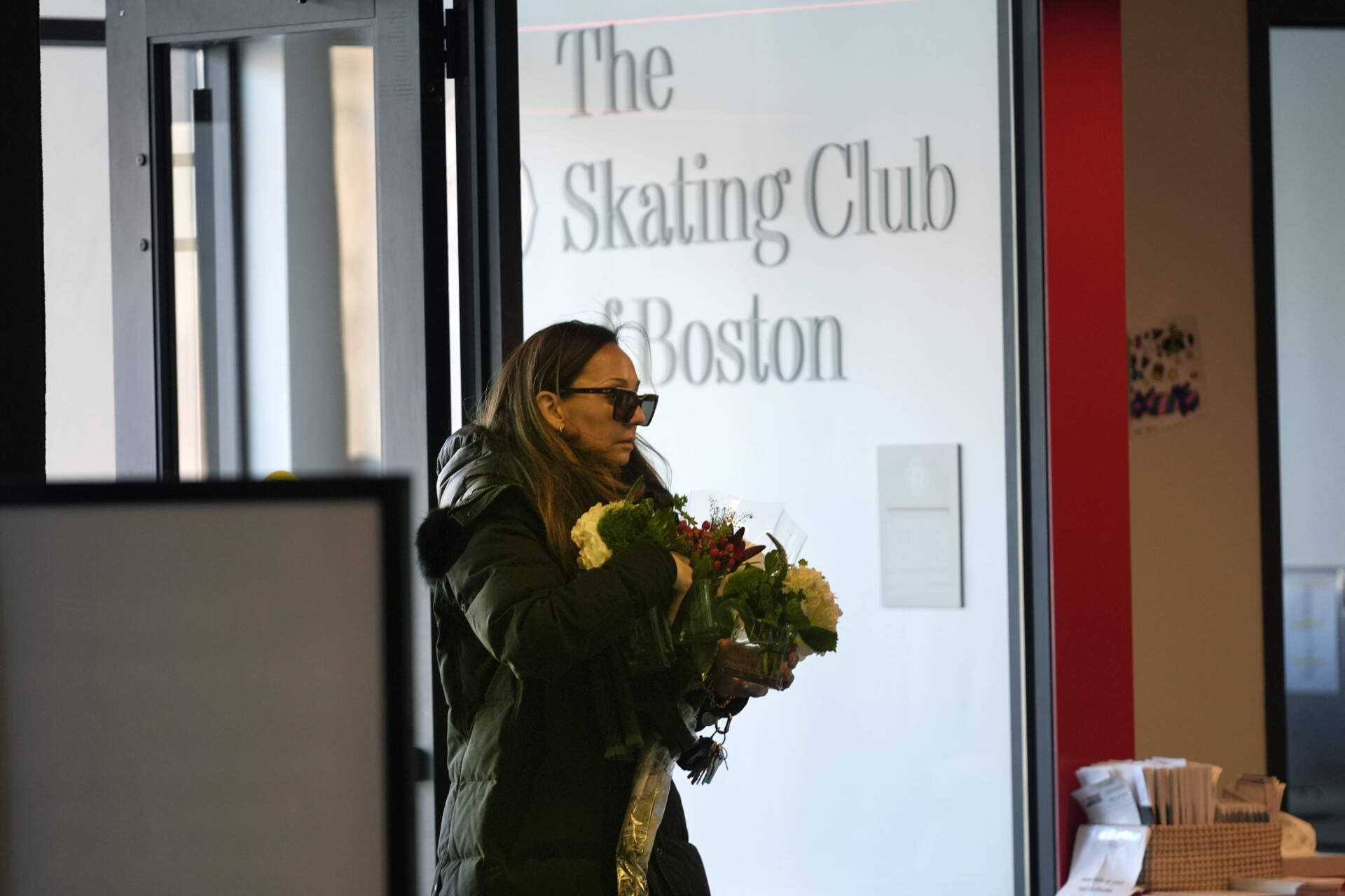 A woman brings flowers to The Skating Club of Boston in Norwood, Massachusetts. (Robert F. Bukaty/AP)