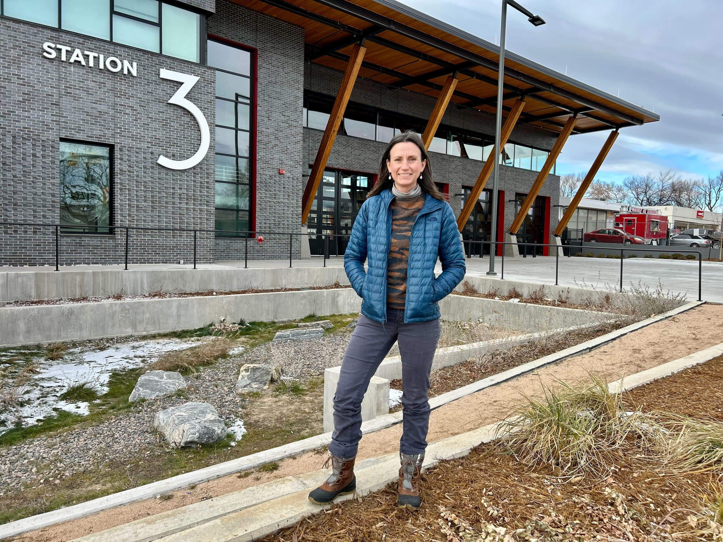 Emily Freeman, policy advisor for a circular economy in Boulder, stands outside the city’s newest fire station. Dozens of steel beams were salvaged from a nearby hospital deconstruction project and reused in the construction of the fire station. (Peter O'Dowd/Here & Now)