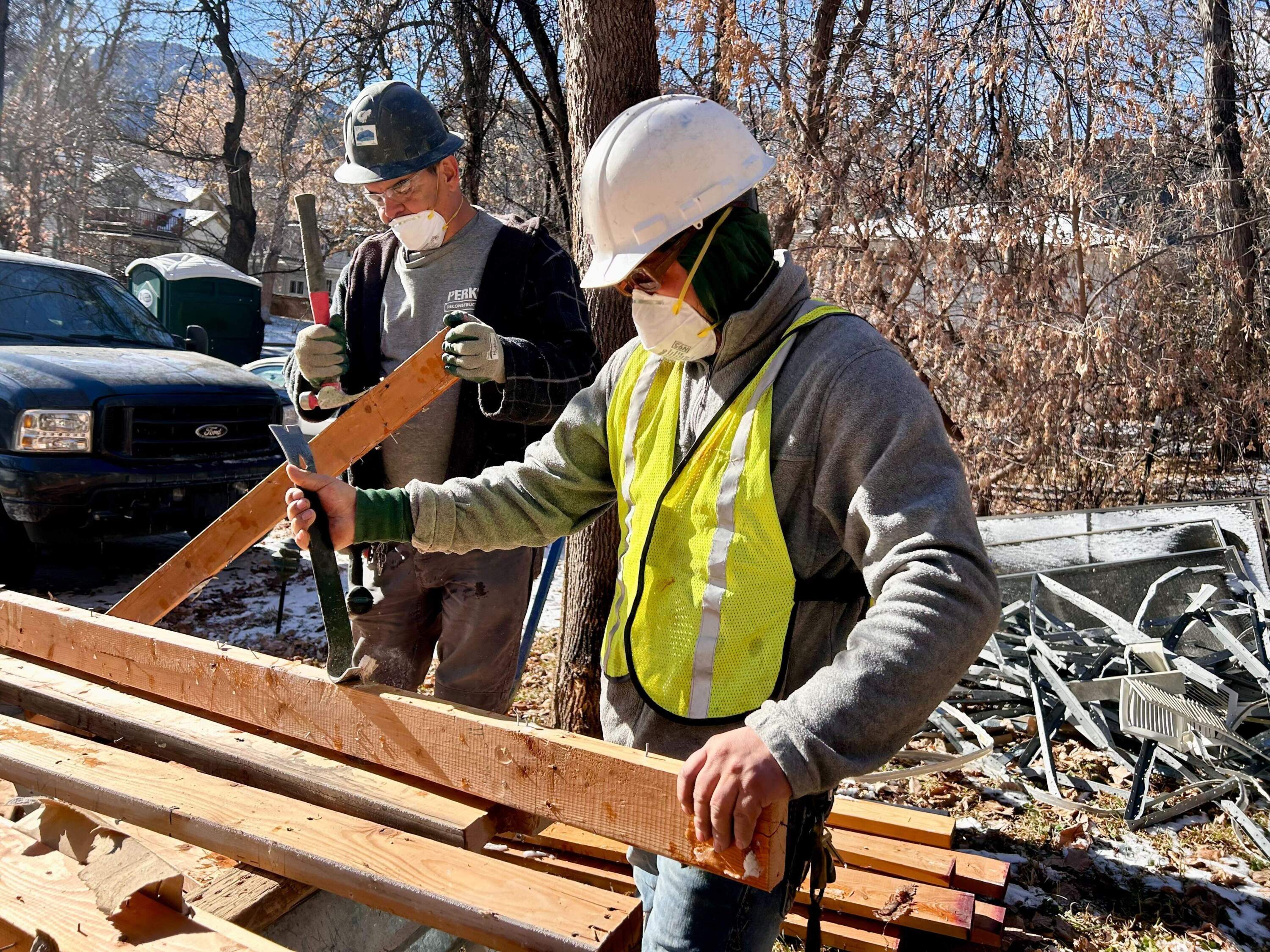 Crews at a deconstruction site in Boulder, Colorado, remove the nails from scraps of lumber. The wood came from a single-family home and will be processed and then resold. (Peter O'Dowd/Here & Now)