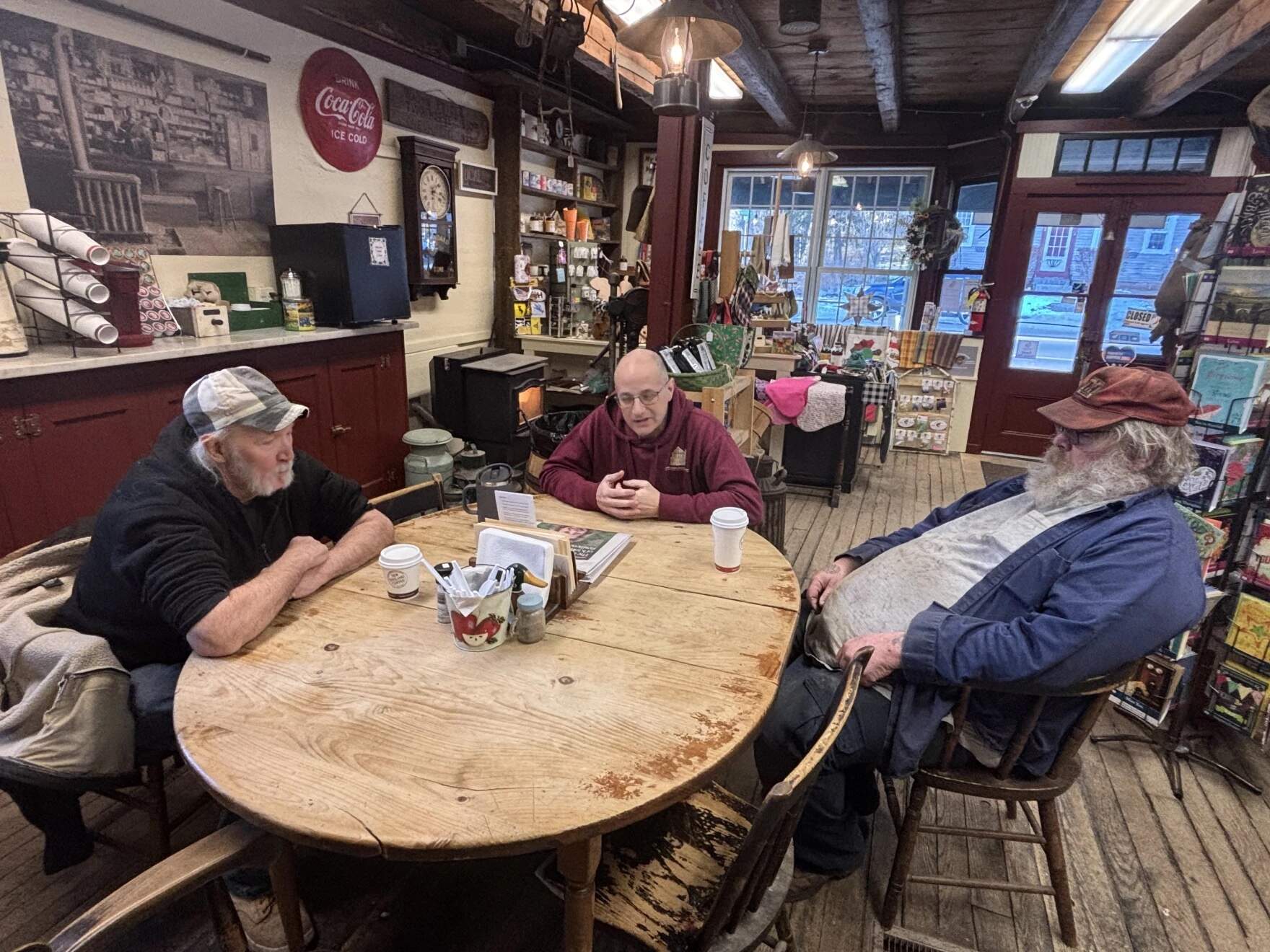After his wife's unexpected death, Dave Dauphinais (center) is trying to preserve her beloved Tuftonboro General Store — and her legacy. Guy Pike (left) and Wayne Perkins (right) are two of the store's regulars. (Annmarie Timmins/NHPR)