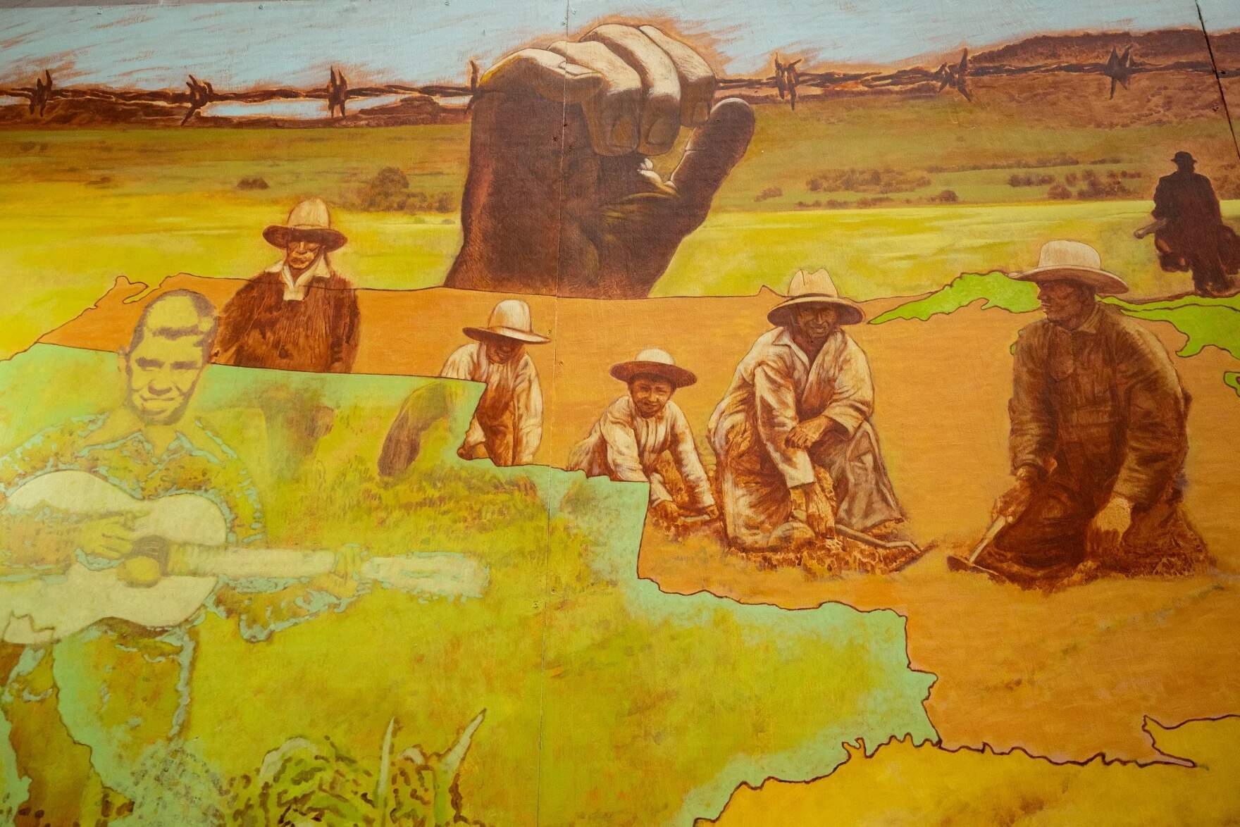 Muralist Carlos Hernández Chávez included a portrait of himself with his guitar in “Sugar Beet Workers” alongside workers with the faces of family members. (Tyler Russell/Connecticut Public)