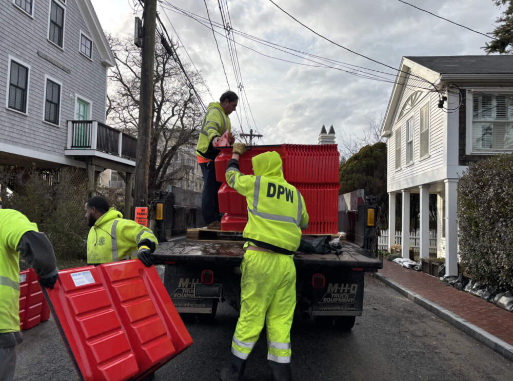 DPW workers unload red plastic flood barriers from a truck and unload them in the East End for the first time. (Eve Zuckoff/CAI)