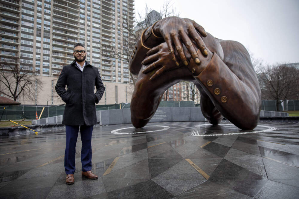 The author, CEO of Embrace Boston, stands by the embrace sculpture at the Boston Common. (Robin Lubbock/WBUR)