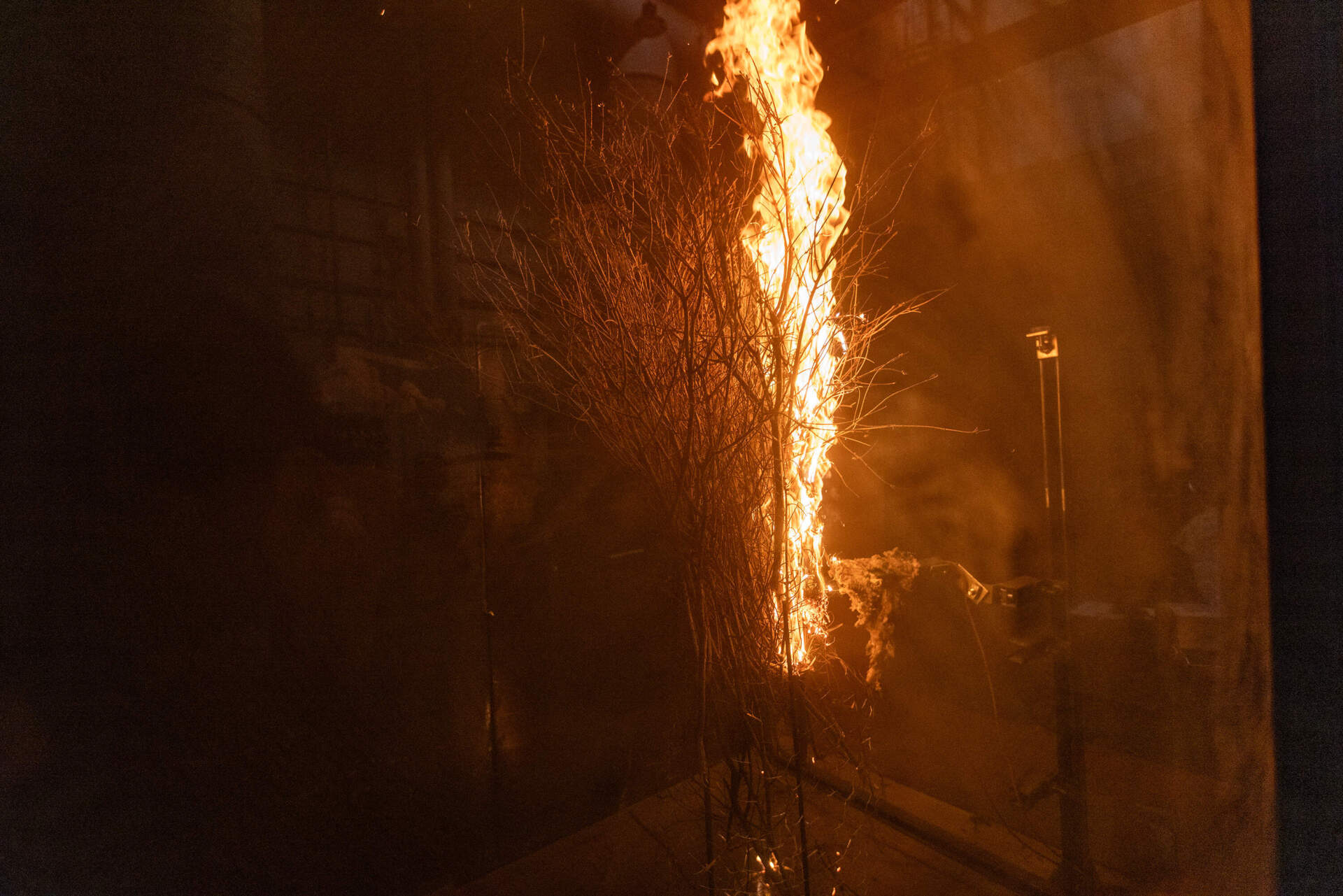 Fernando Ebensperger sets the brush on fire using an electric igniter inside the wind tunnel to begin the wind test. (Jesse Costa/WBUR)