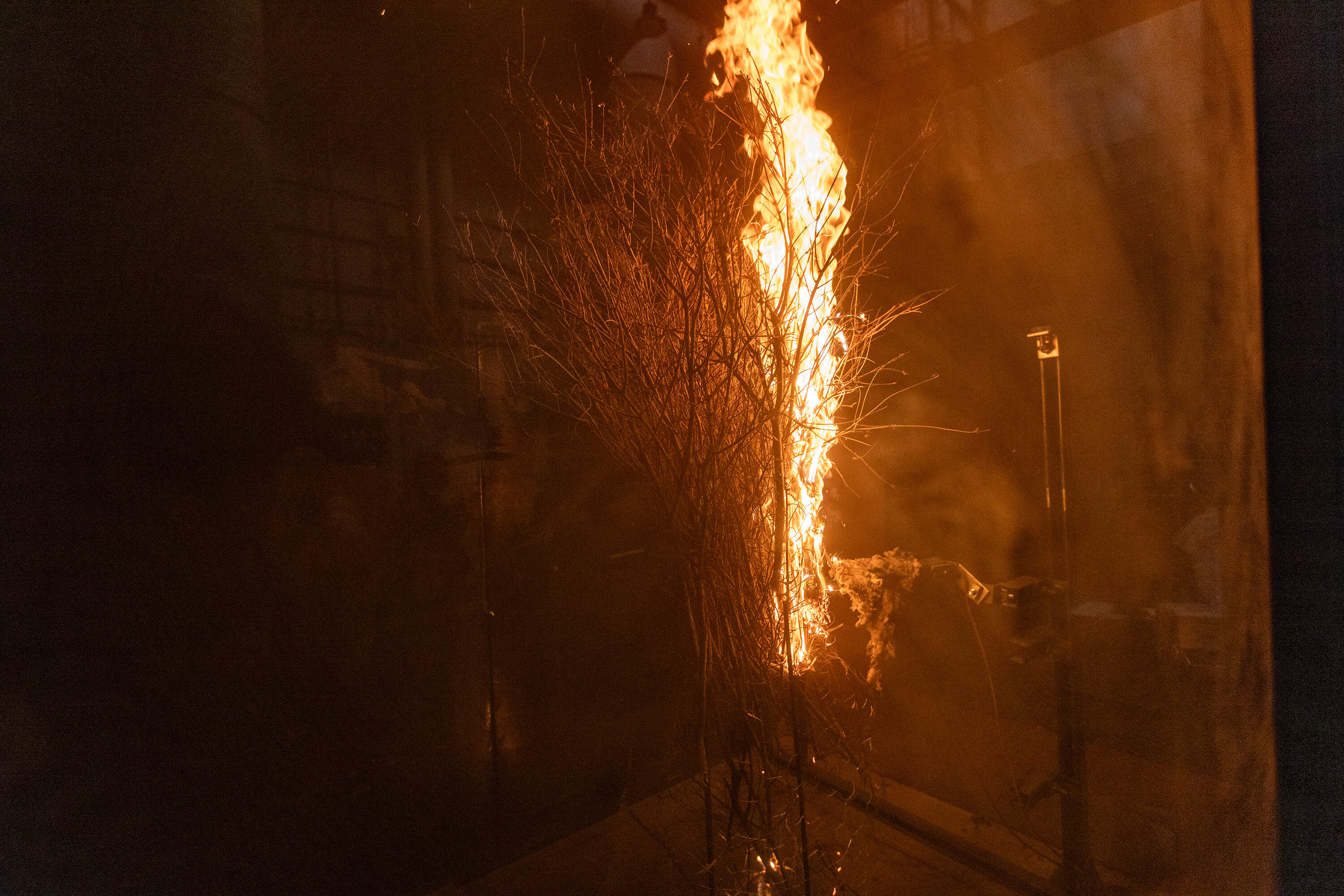 Fernando Ebensperger sets the brush on fire using an electric igniter inside the wind tunnel to begin the wind test. (Jesse Costa/WBUR)