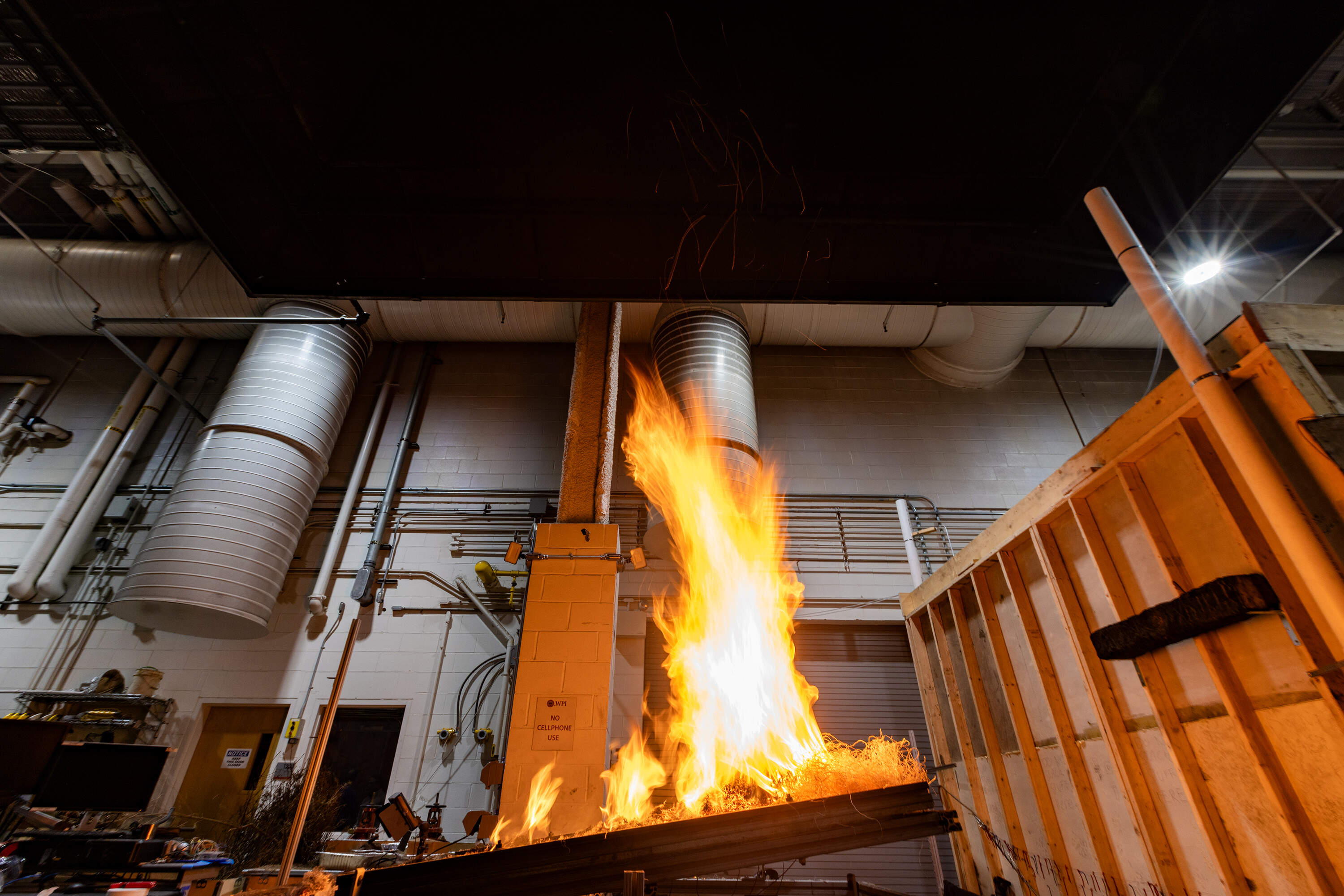 Fire leaps from the tilted table where fire protection engineering students are conducting a test to see how a burning fire reacts to an incline. (Jesse Costa/WBUR)