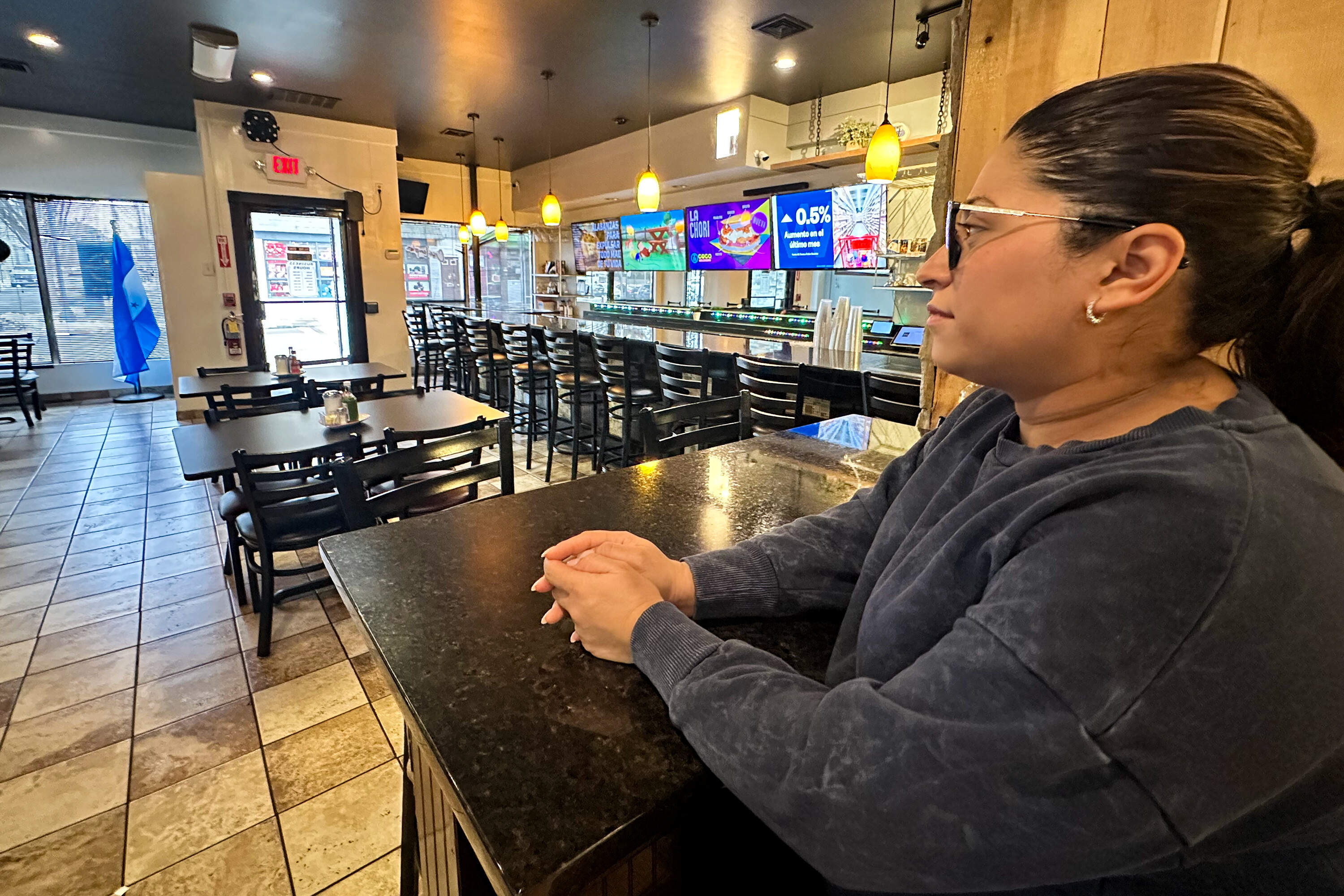 Casa Lempira owner Marelin Pineda looks out at her empty restaurant at lunchtime. She said rumors were going around that ICE agents had conducted a raid at the business. (Simón Rios/WBUR)
