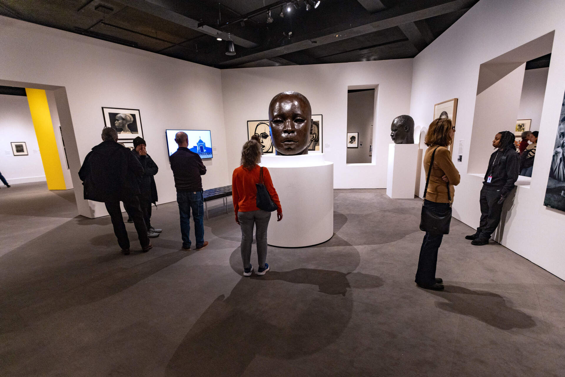 Museum patrons look at a half-size maquette of “Eternal Presence,” at the “Witnessing Humanity: The Art of John Wilson” exhibit at the Museum of Fine Arts, Boston. The actual statue is seven feet tall and stands on the grounds of the National Center of Afro-American Artists in Roxbury. (Jesse Costa/WBUR)